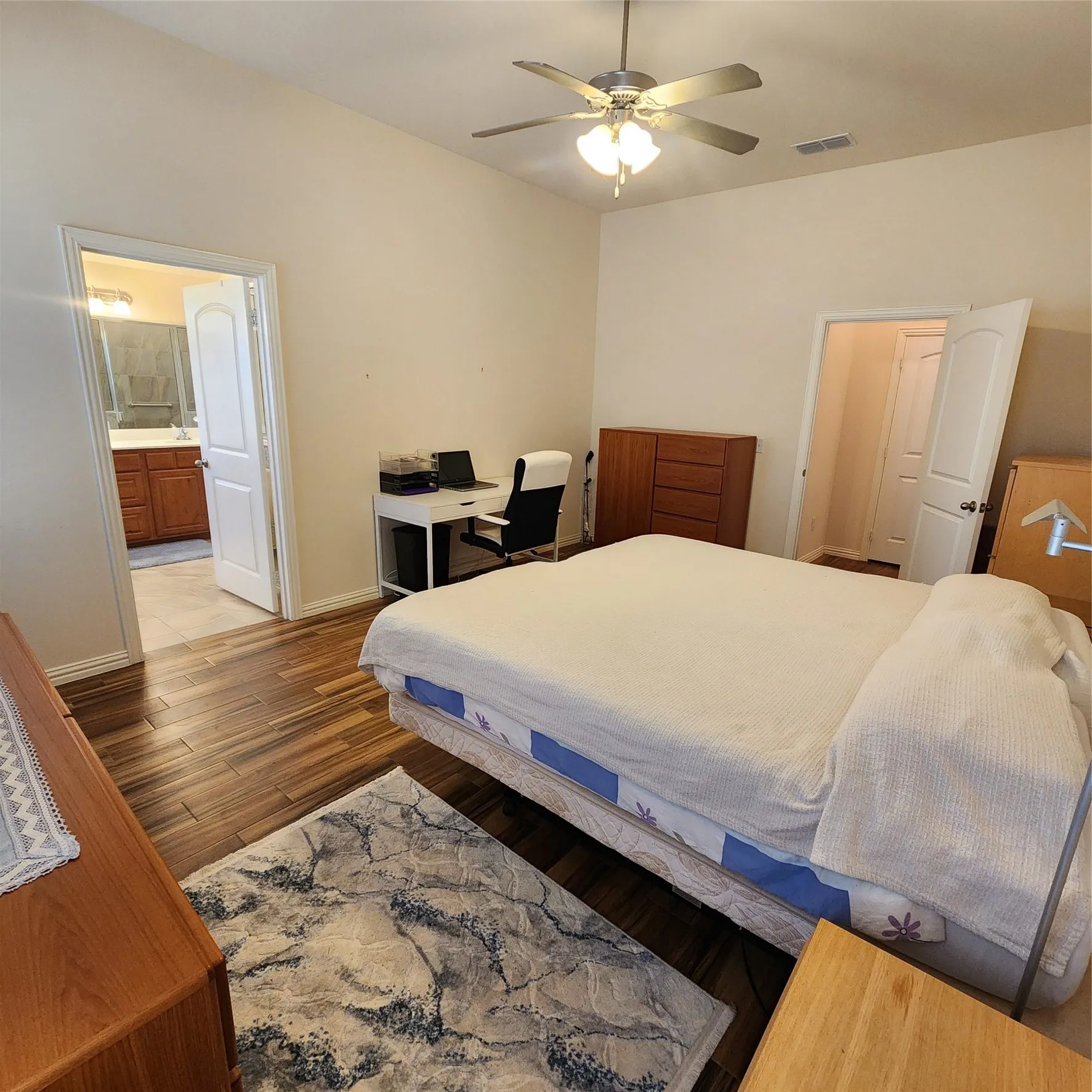 Vaulted ceiling, wood-finish flooring, ceiling fan with integrated lighting, and an en-suite bathroom with a double vanity