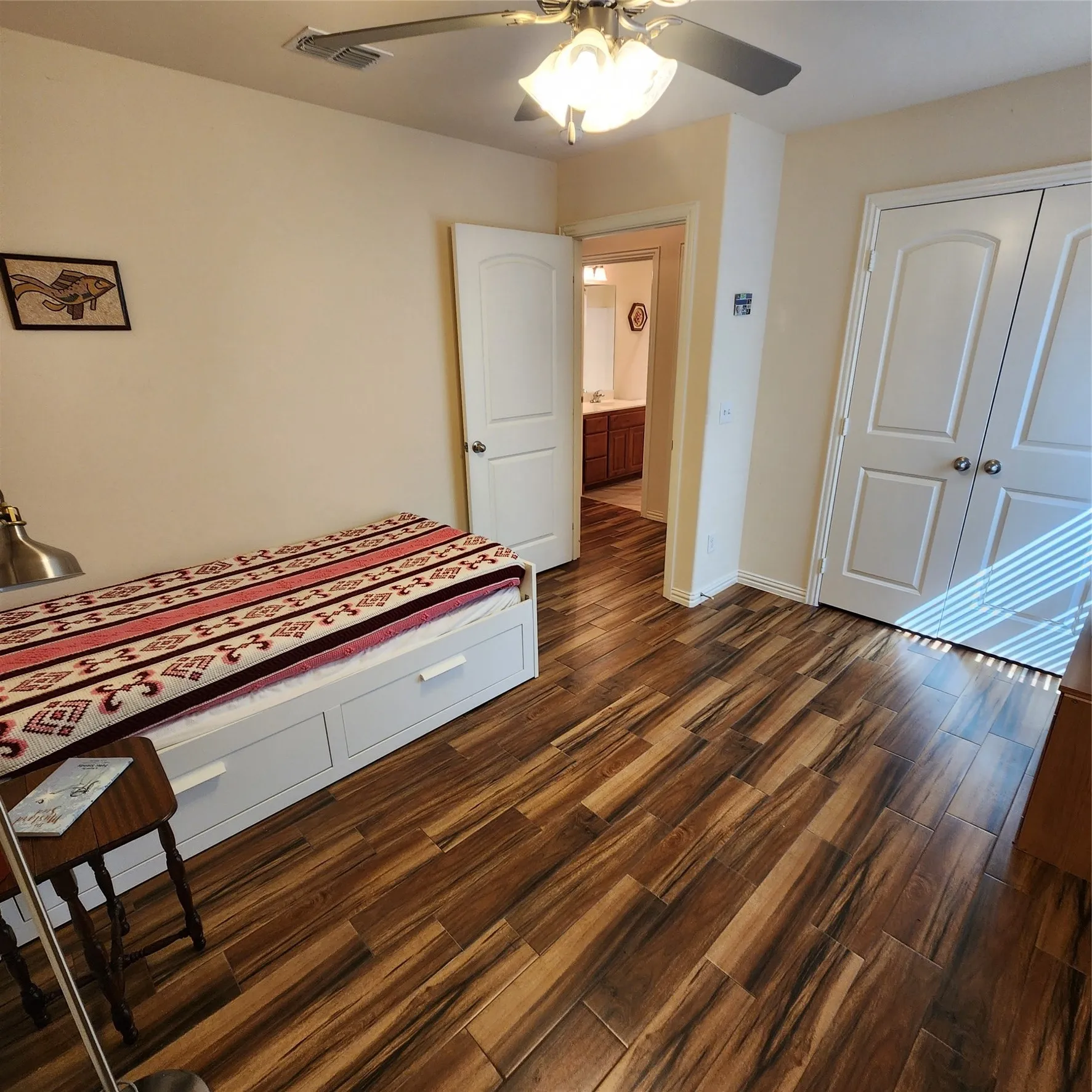 Wood-finish flooring throughout, ceiling fan with integrated lighting, and white paneled doors
