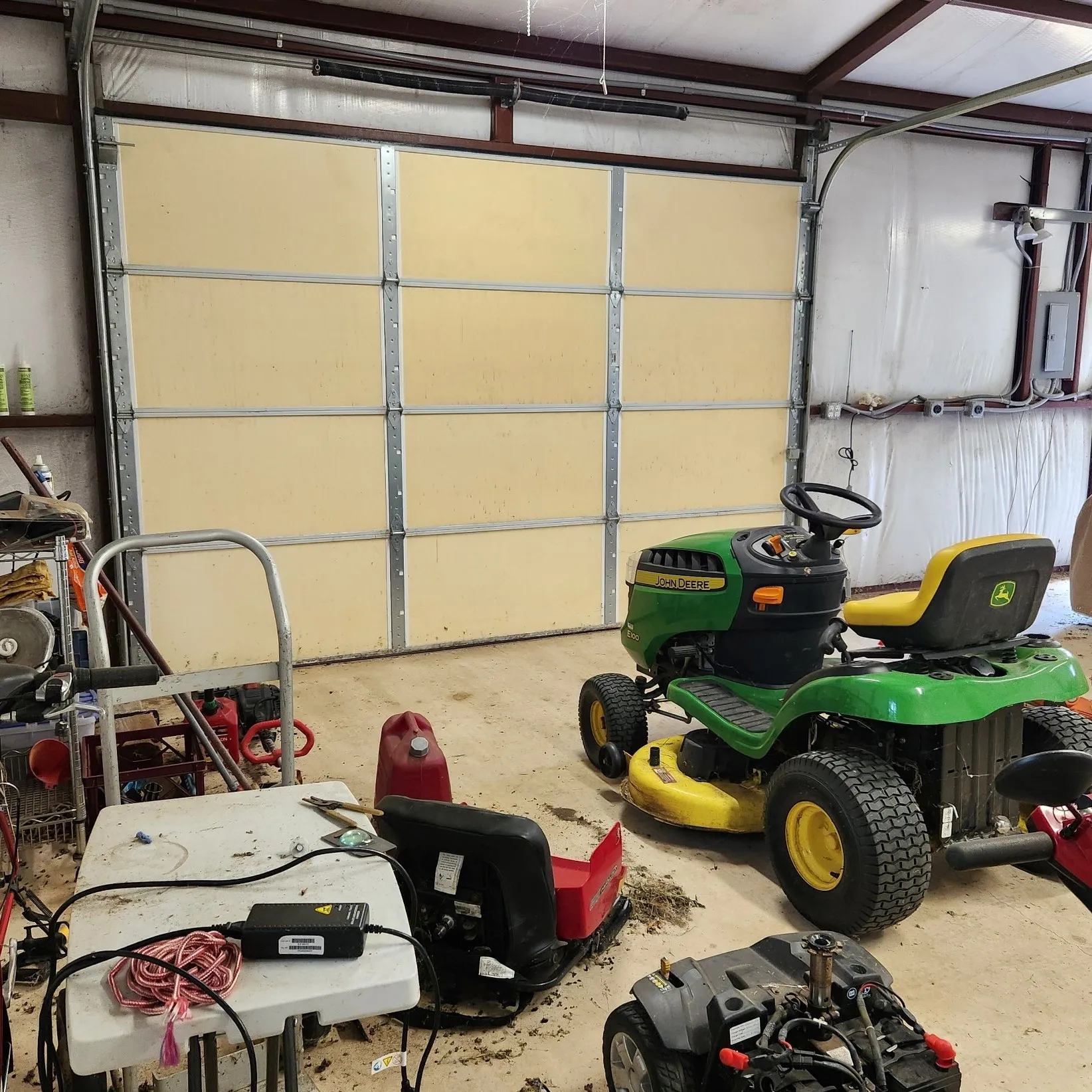 Interior of the approx. 20'x30' metal auxiliary building showing insulated walls & roof and concrete floor and featuring a roll-up door and a side entry door