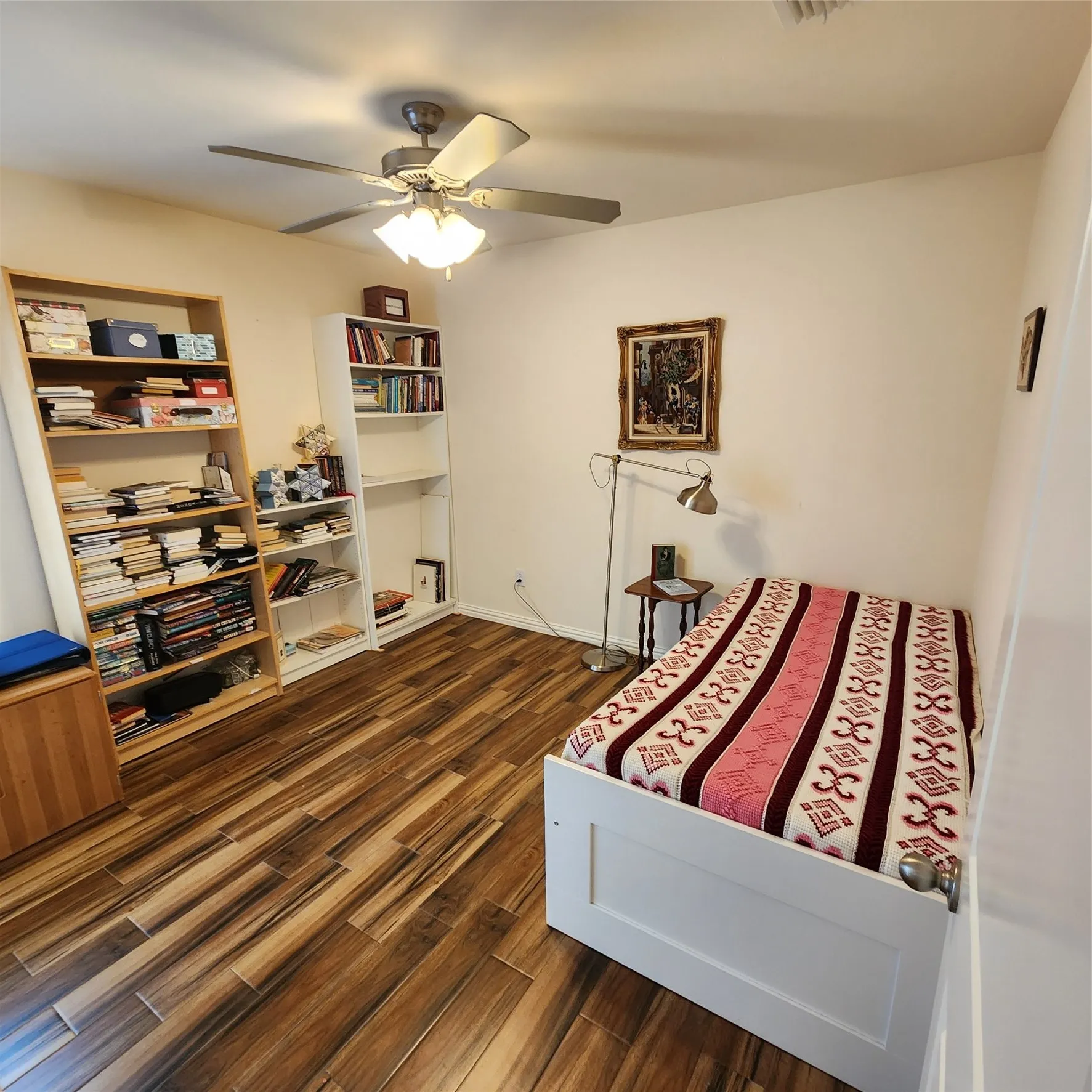 Wood-finish flooring with varied tones, ceiling fan with integrated lighting, and neutral wall paint