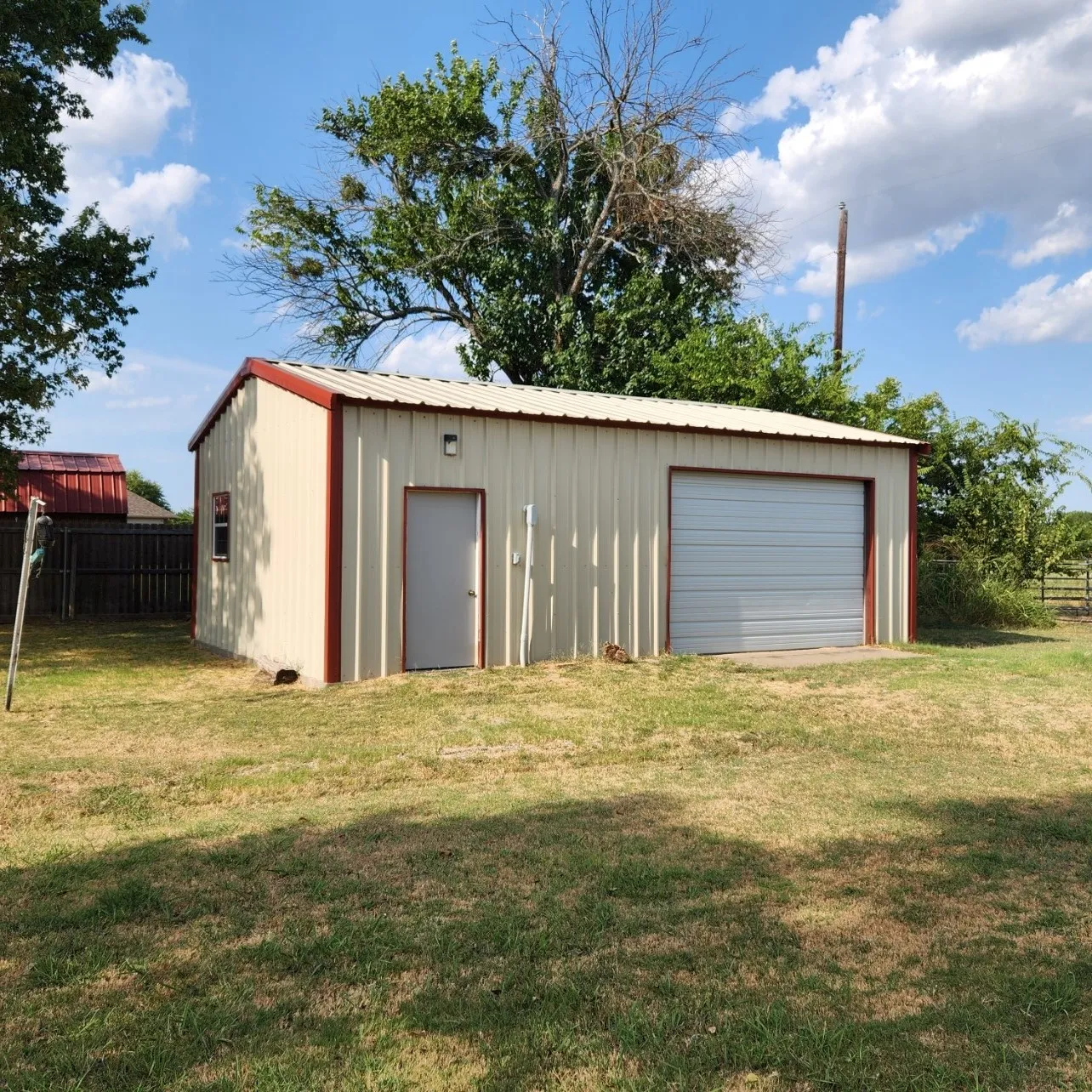 Approx. 20'x30' metal auxiliary building with concrete floor and featuring a roll-up door and a side entry door