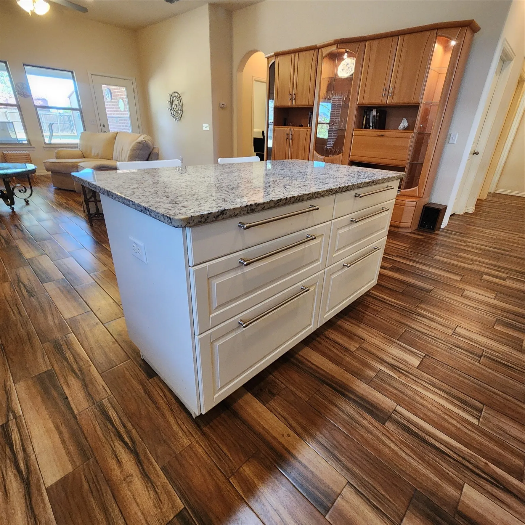 Kitchen island with white paneled cabinetry, polished chrome hardware, and a stone countertop