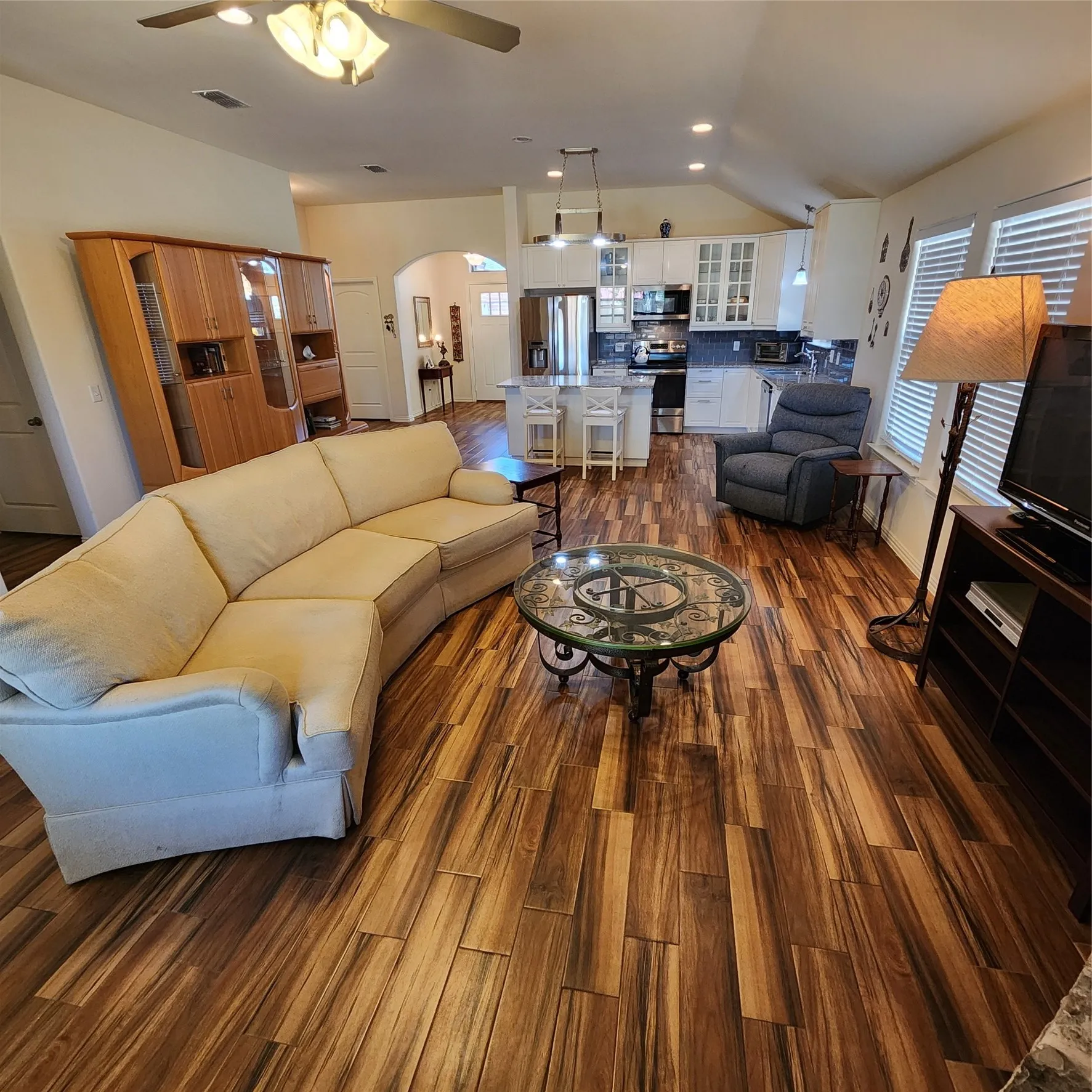 Open-concept living space featuring wood-finish flooring, vaulted ceilings, a ceiling fan, and recessed lighting.