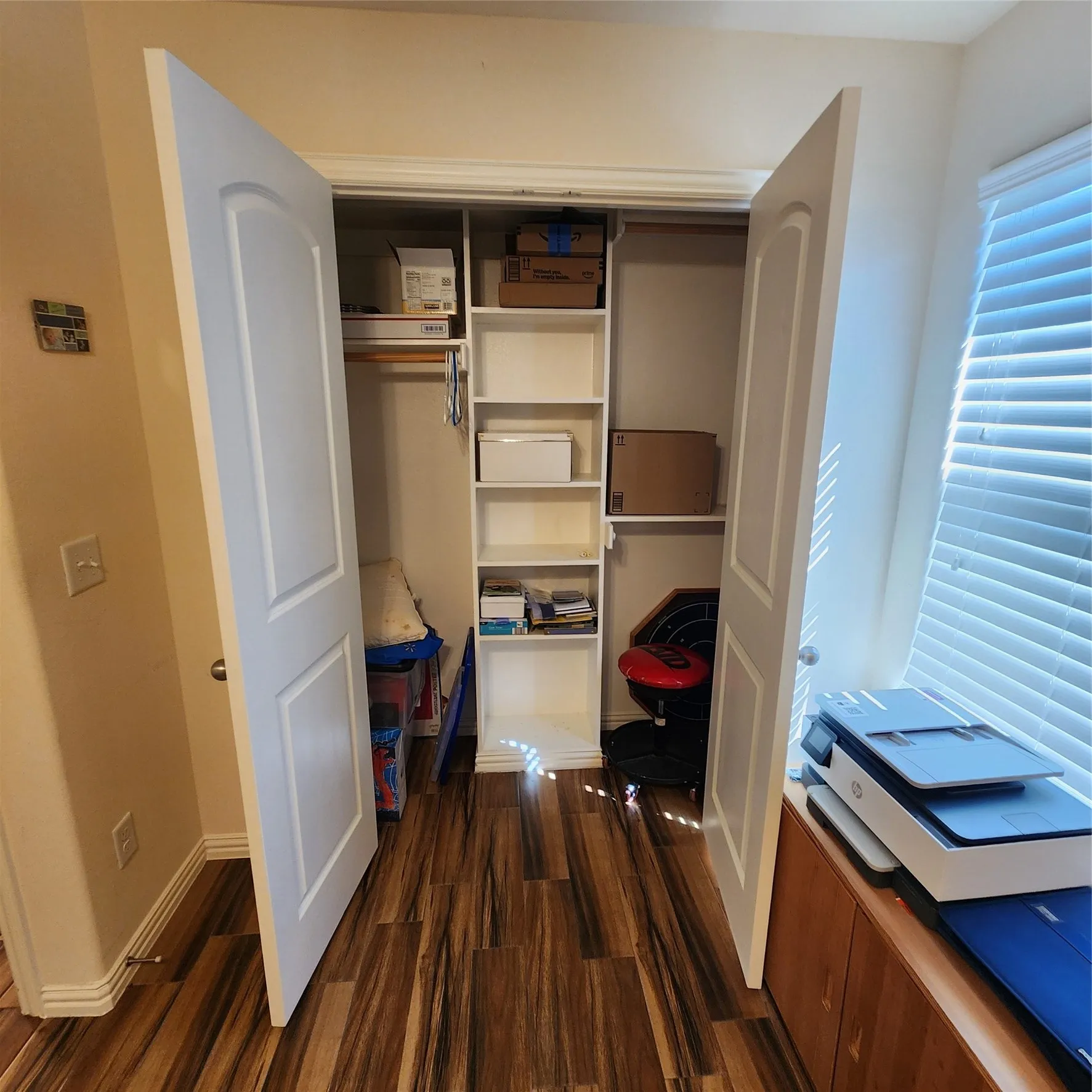 Double bifold doors revealing a built-in shelving unit, equipped with a clothing rod and multiple storage shelves