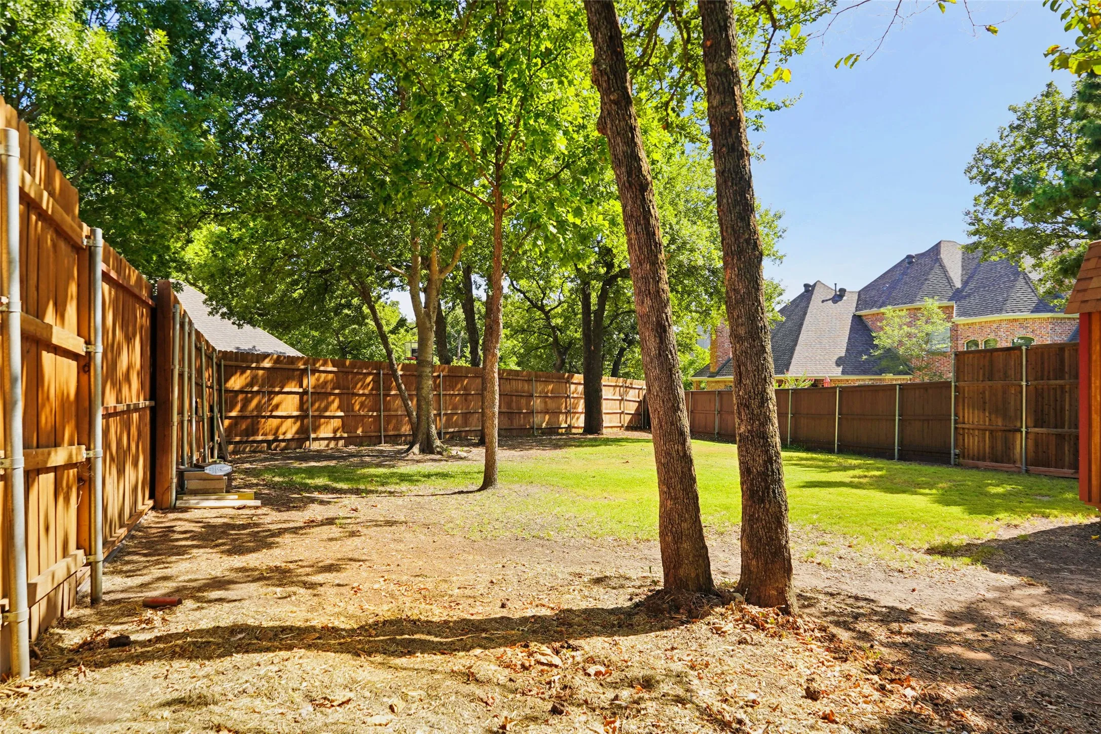 Expansive backyard space with mature trees and wood privacy fencing