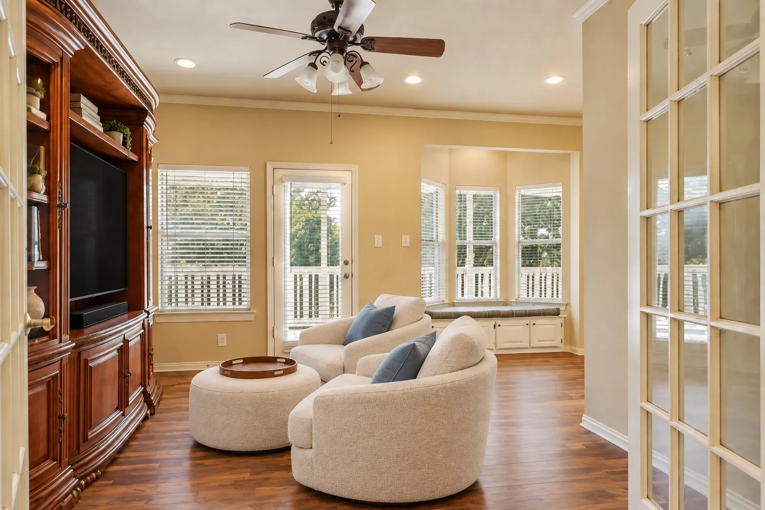 Wood-finish flooring throughout, featuring a built-in media cabinet, ceiling fan, and recessed lighting