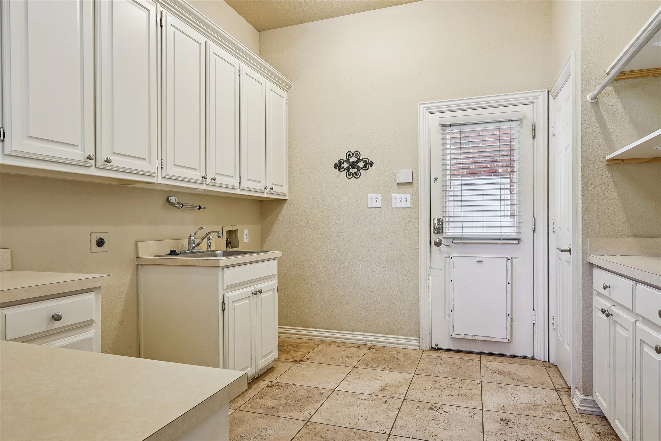 Tile flooring, white cabinetry, integrated utility sink, neutral countertops, and a vaulted ceiling