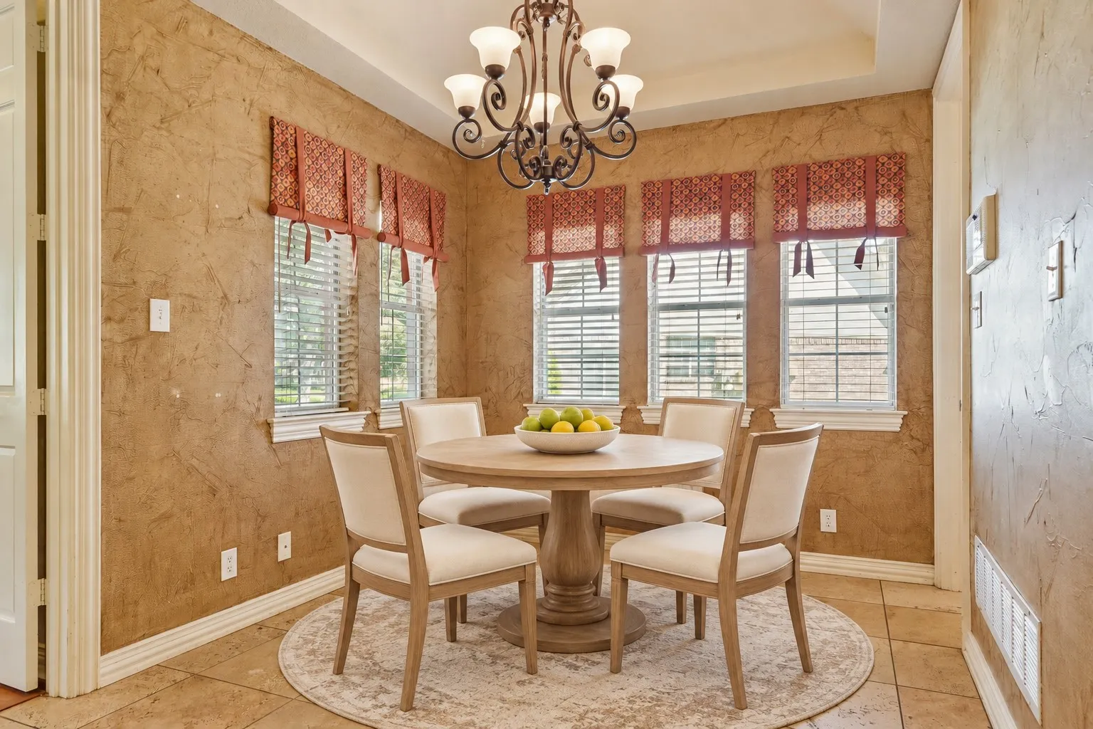 Recessed ceiling with an ornate chandelier, textured wall finish, and multiple windows