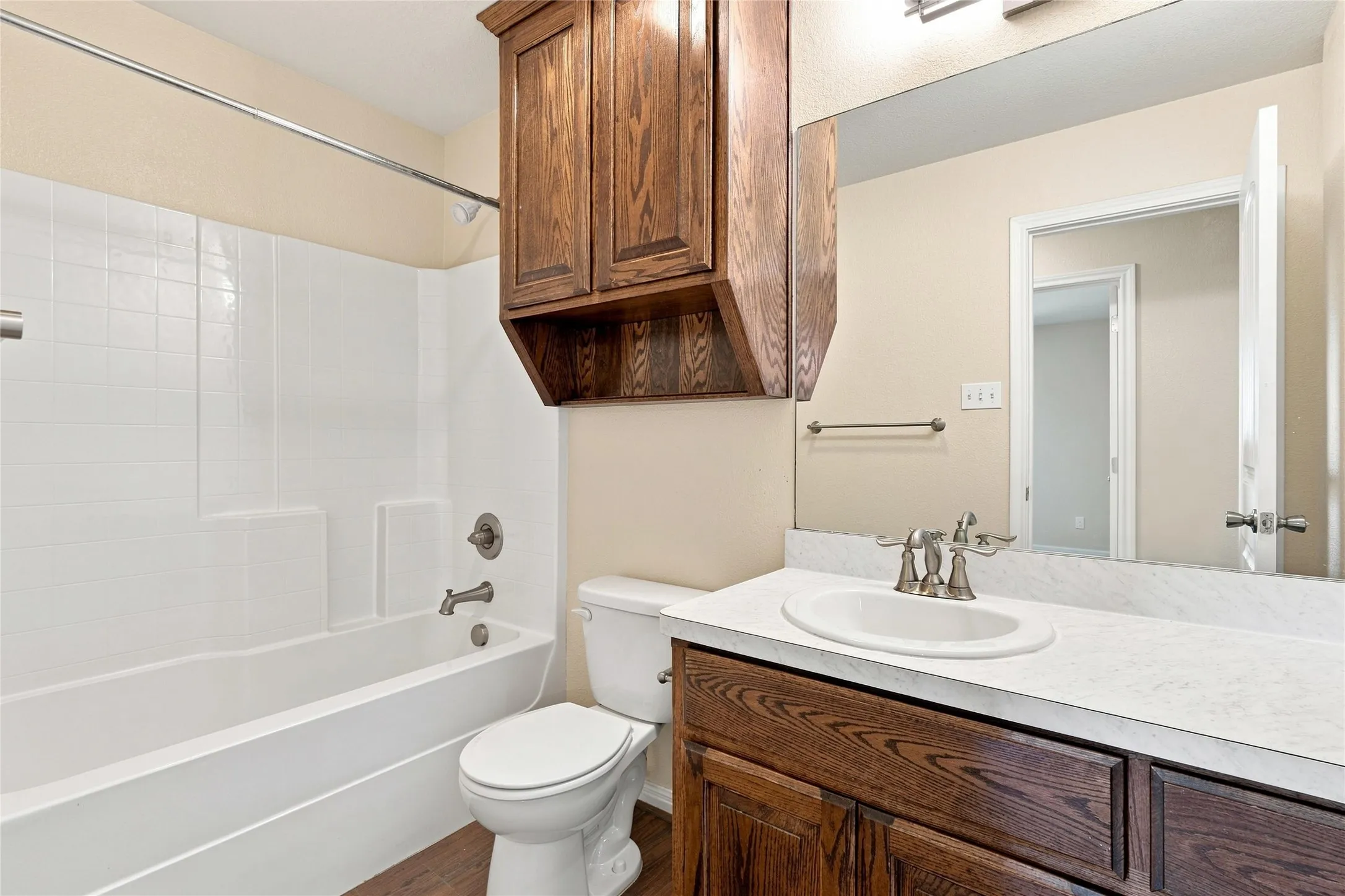 Bathroom with a vanity featuring a wood-finish cabinet, a white countertop with an integrated sink, and a large mirror