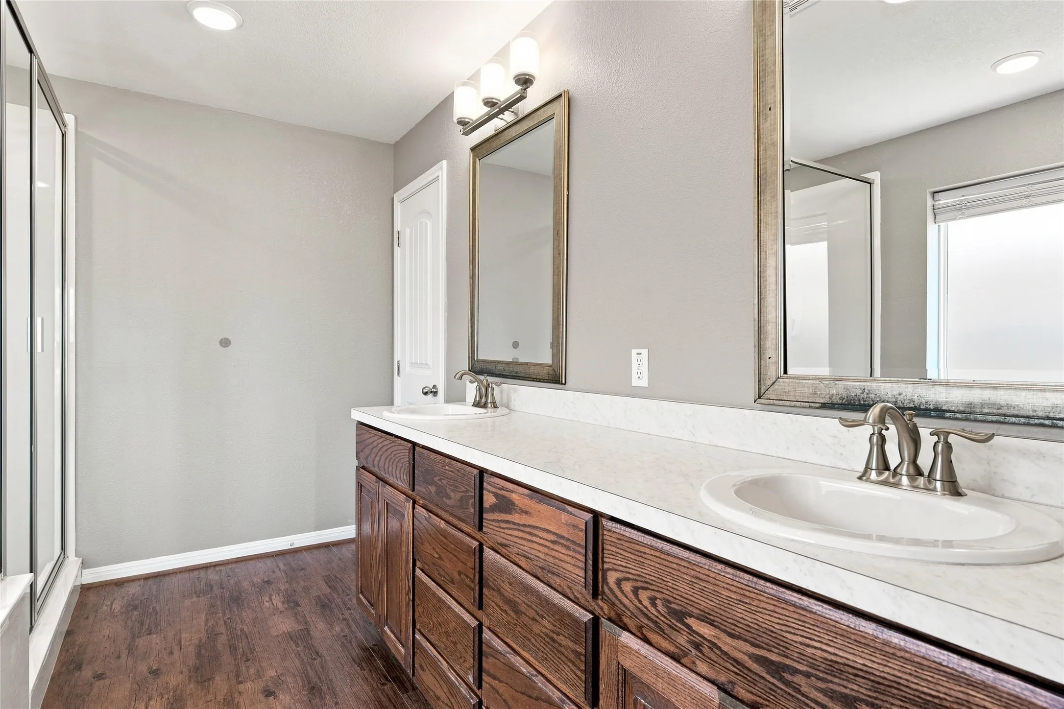 Dual vanity with wood-finish cabinetry, white countertops, and undermount sinks