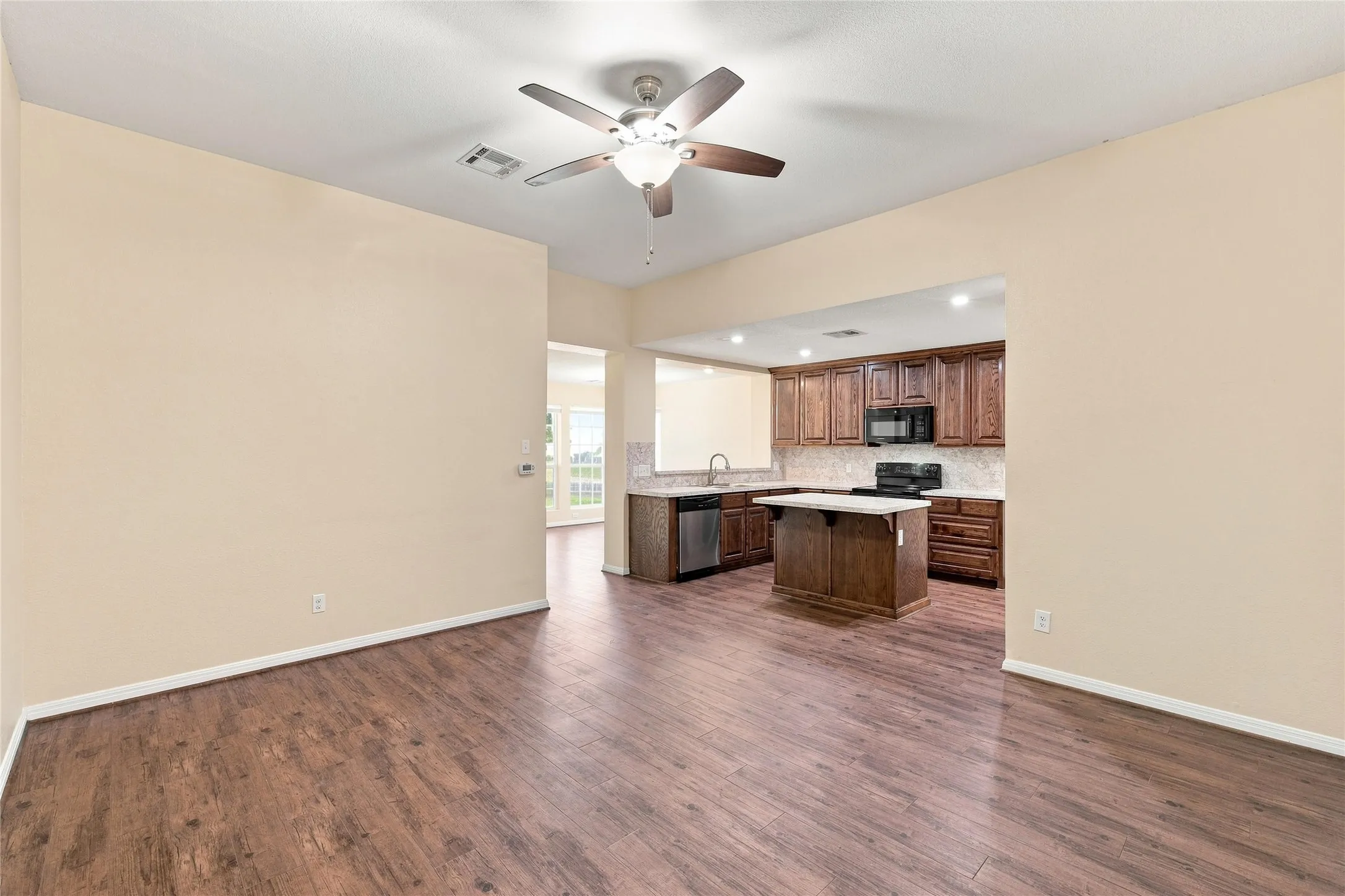 Wood-finish flooring throughout, with a ceiling fan in the foreground