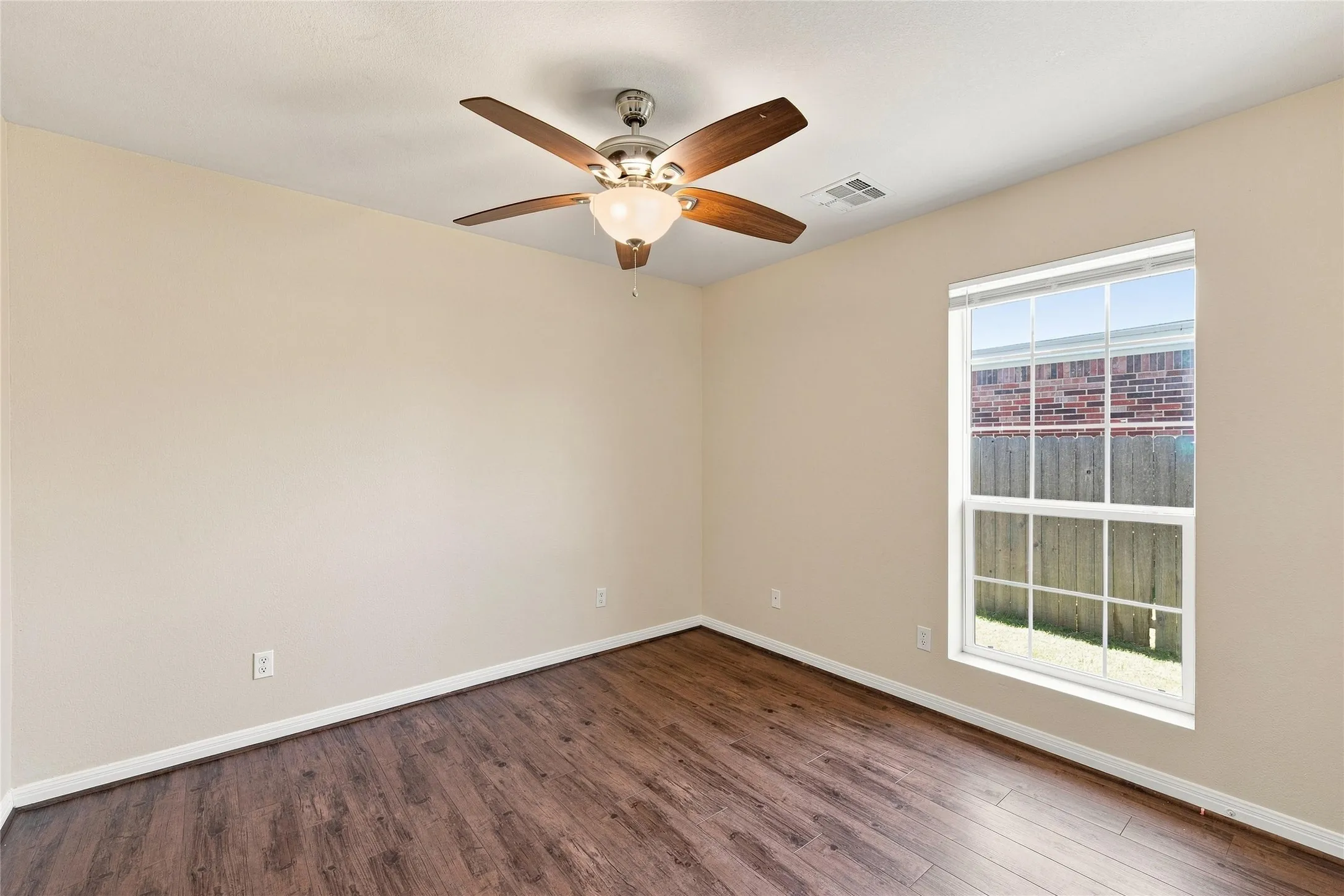 Room featuring wood-finish flooring, a ceiling fan with integrated lighting, and a single-pane window