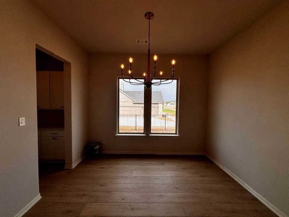 Wood-finish flooring with a modern chandelier, dual windows, and recessed lighting