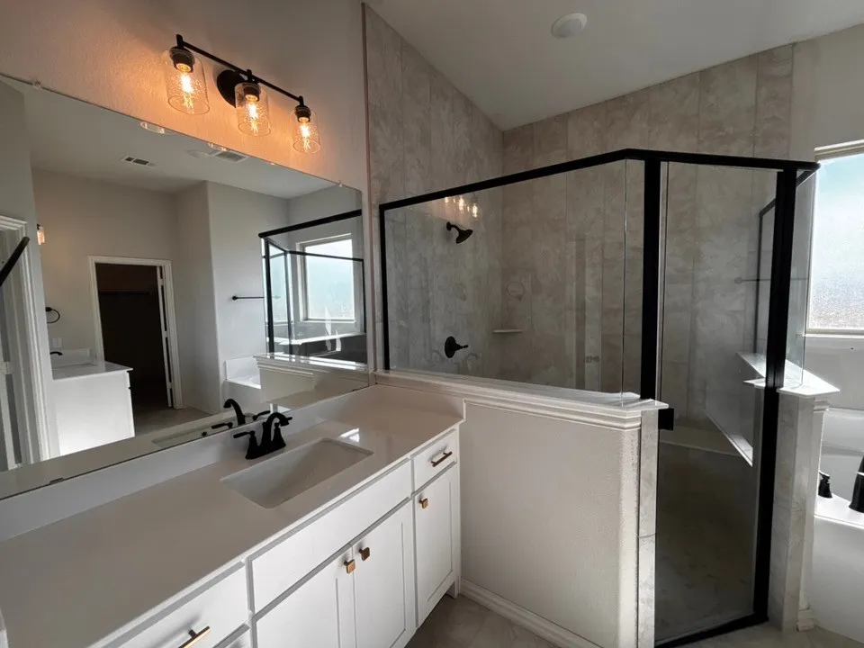 Dual vanities with white cabinetry, matte black fixtures, and gold-tone hardware
