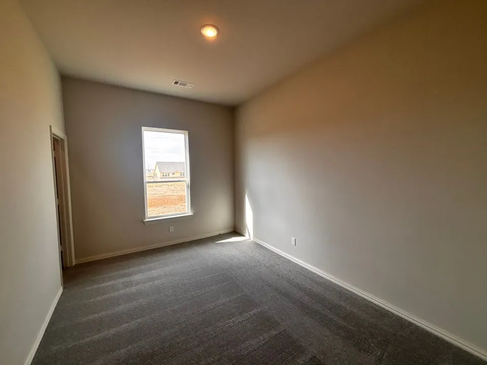 Recessed ceiling light, neutral wall paint, gray patterned carpeting, and white trim