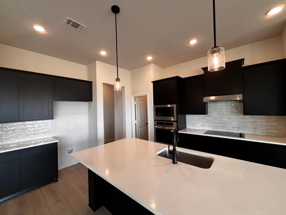 Kitchen featuring dark cabinetry, light countertops, wood-finish flooring, and recessed lighting