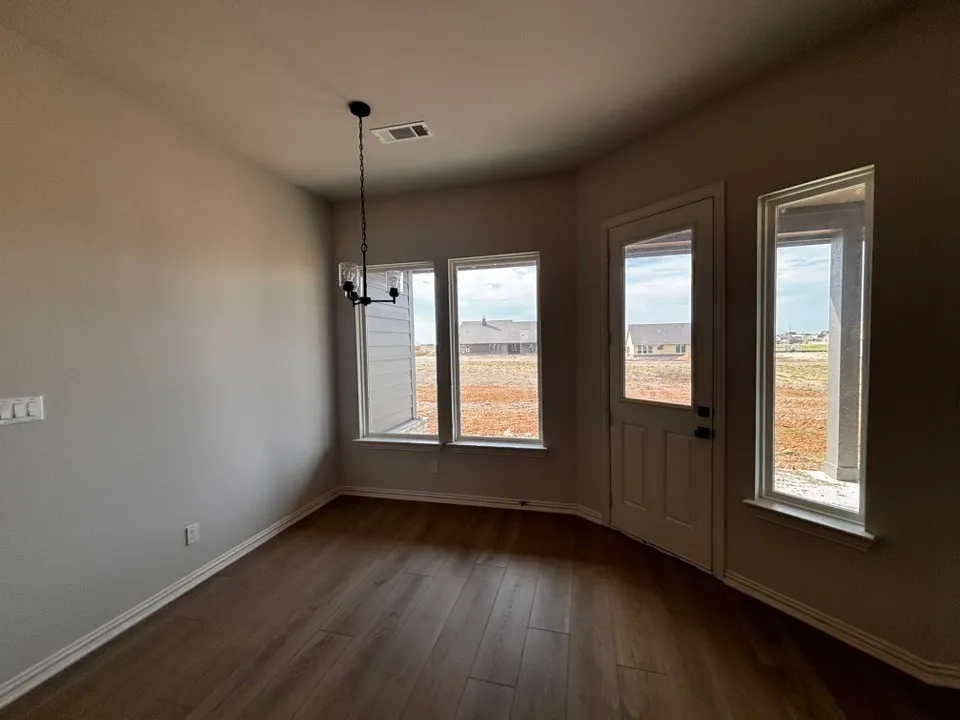 Wood-finish flooring throughout, multiple windows, and a glass-paneled exterior door provide natural illumination