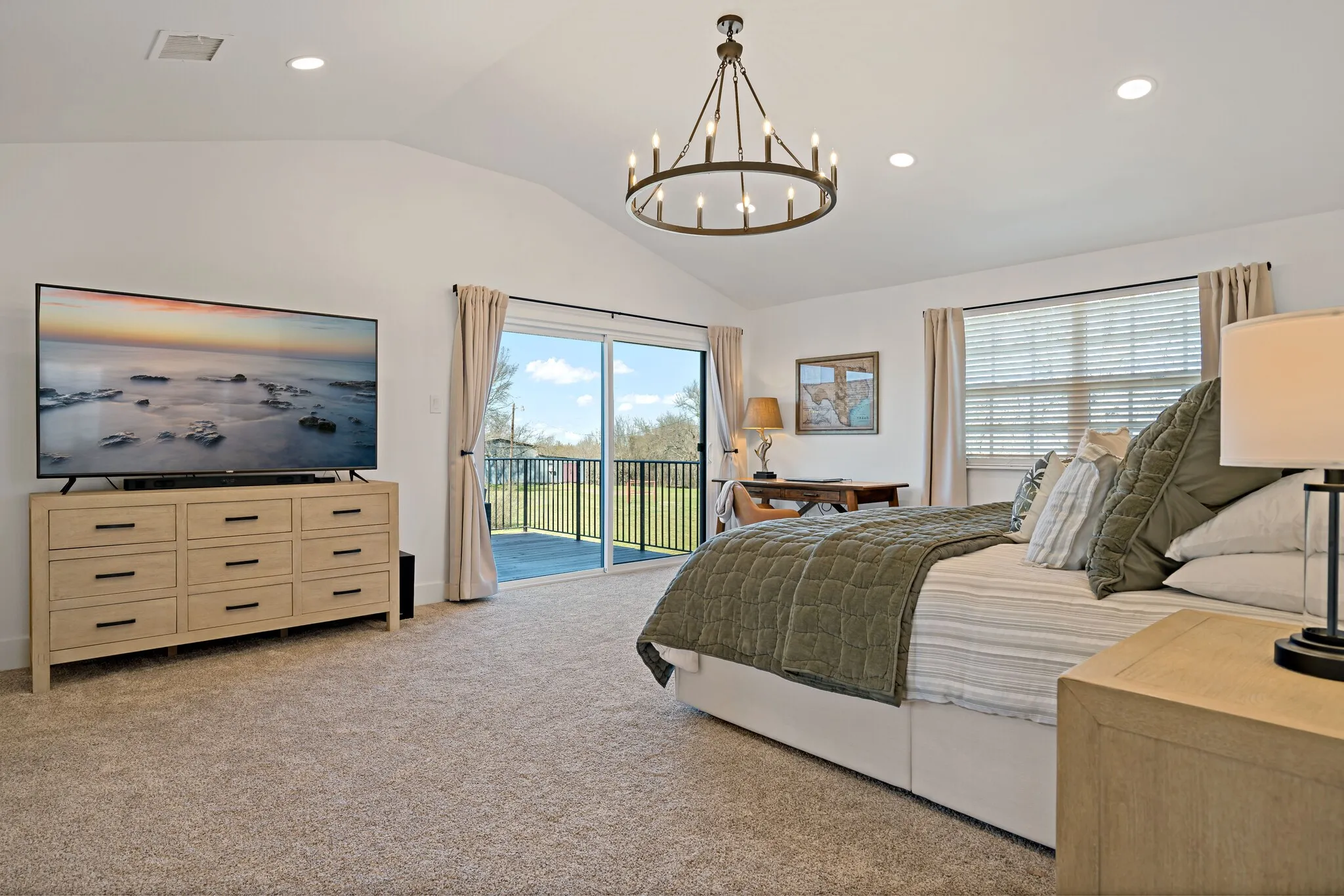 Vaulted ceiling, recessed lighting, sliding glass door to exterior deck, black metal railing, and a rustic-style chandelier