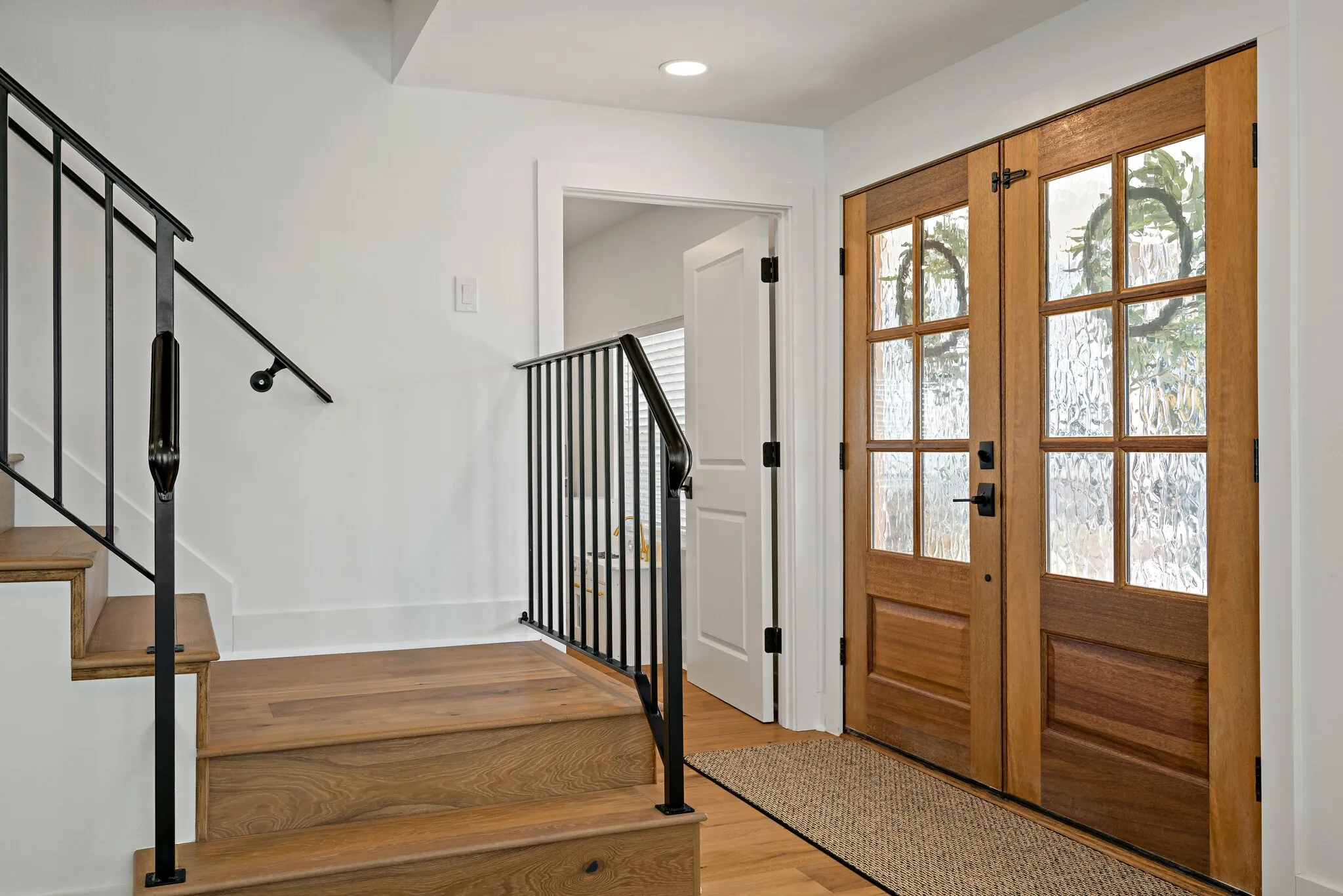 Wood flooring throughout, with a hardwood staircase featuring black metal railings