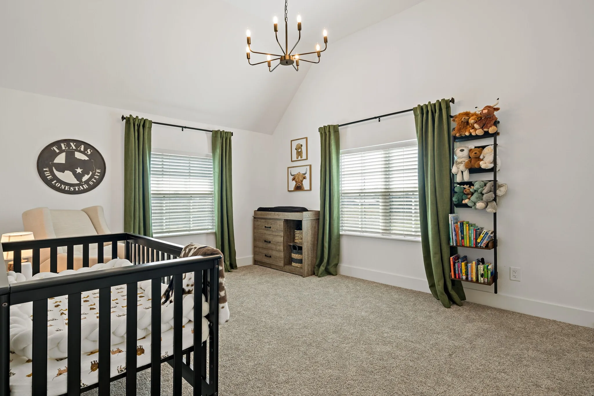 Vaulted ceiling with an overhead chandelier, dual windows with blinds, and carpeted flooring