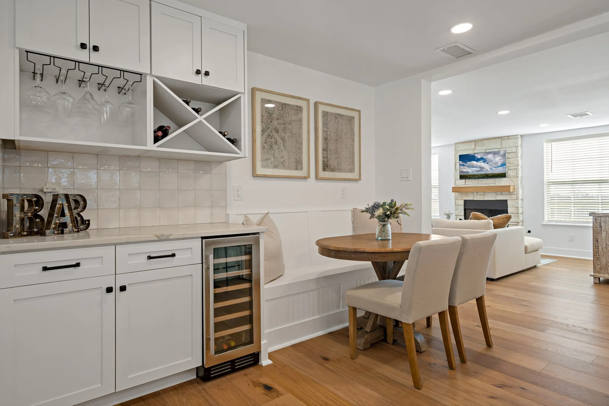 Built-in wine storage, integrated beverage refrigerator, white cabinetry, tile backsplash, and wood flooring
