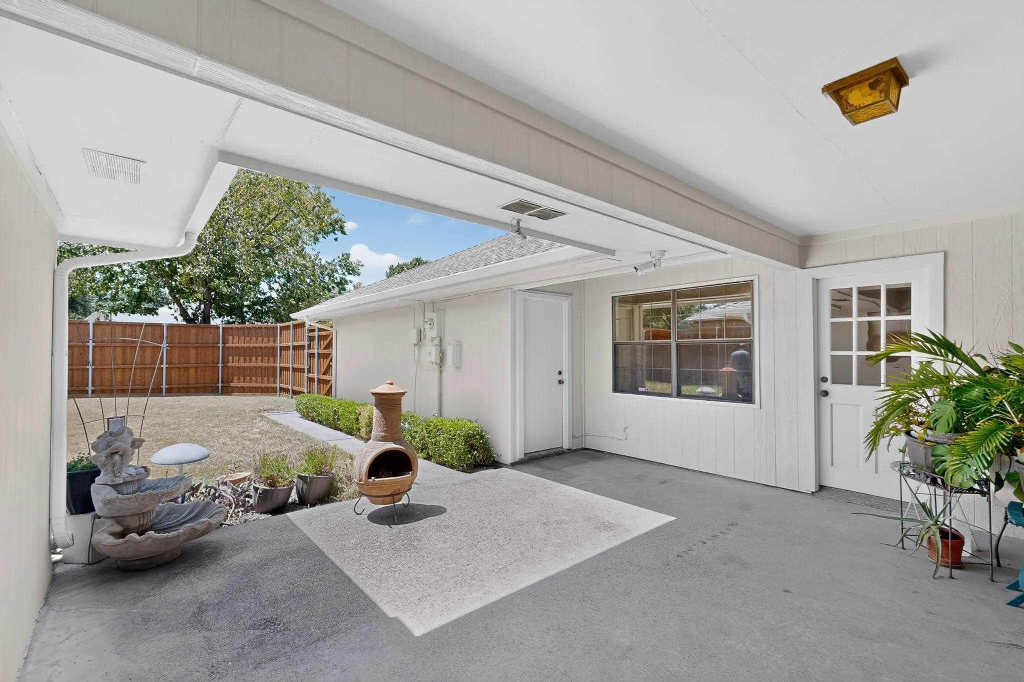 Covered patio with an exterior door, a large window, and a fenced backyard