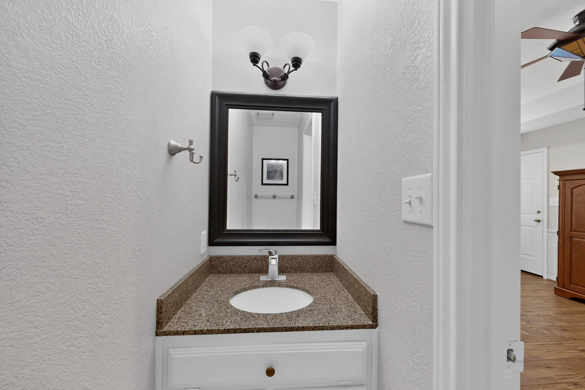 1/2 bath attached to gameroom with Vanity with a granite-look countertop, integrated sink, and brushed nickel faucet