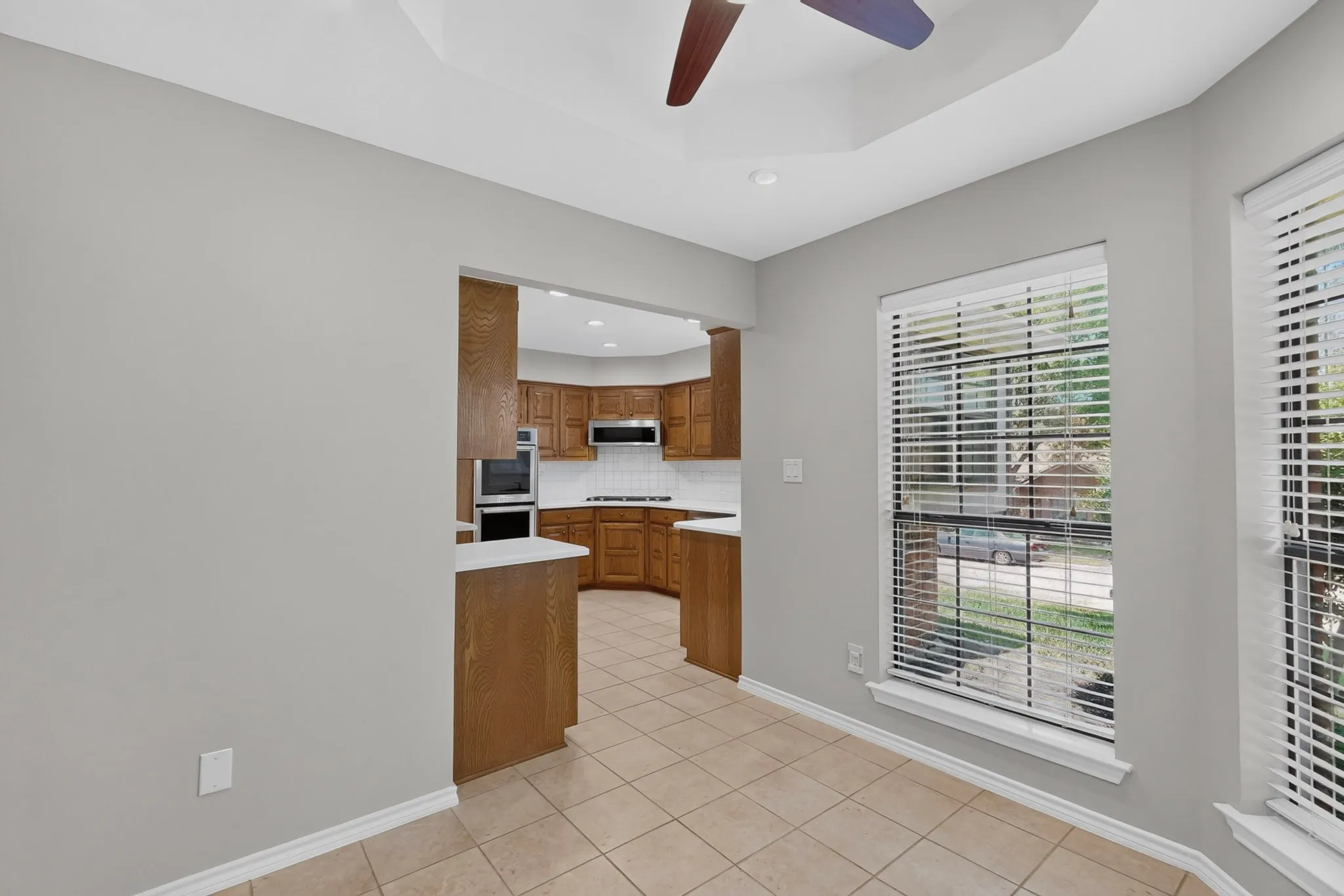 Tray ceiling with ceiling fan, recessed lighting, and tile flooring