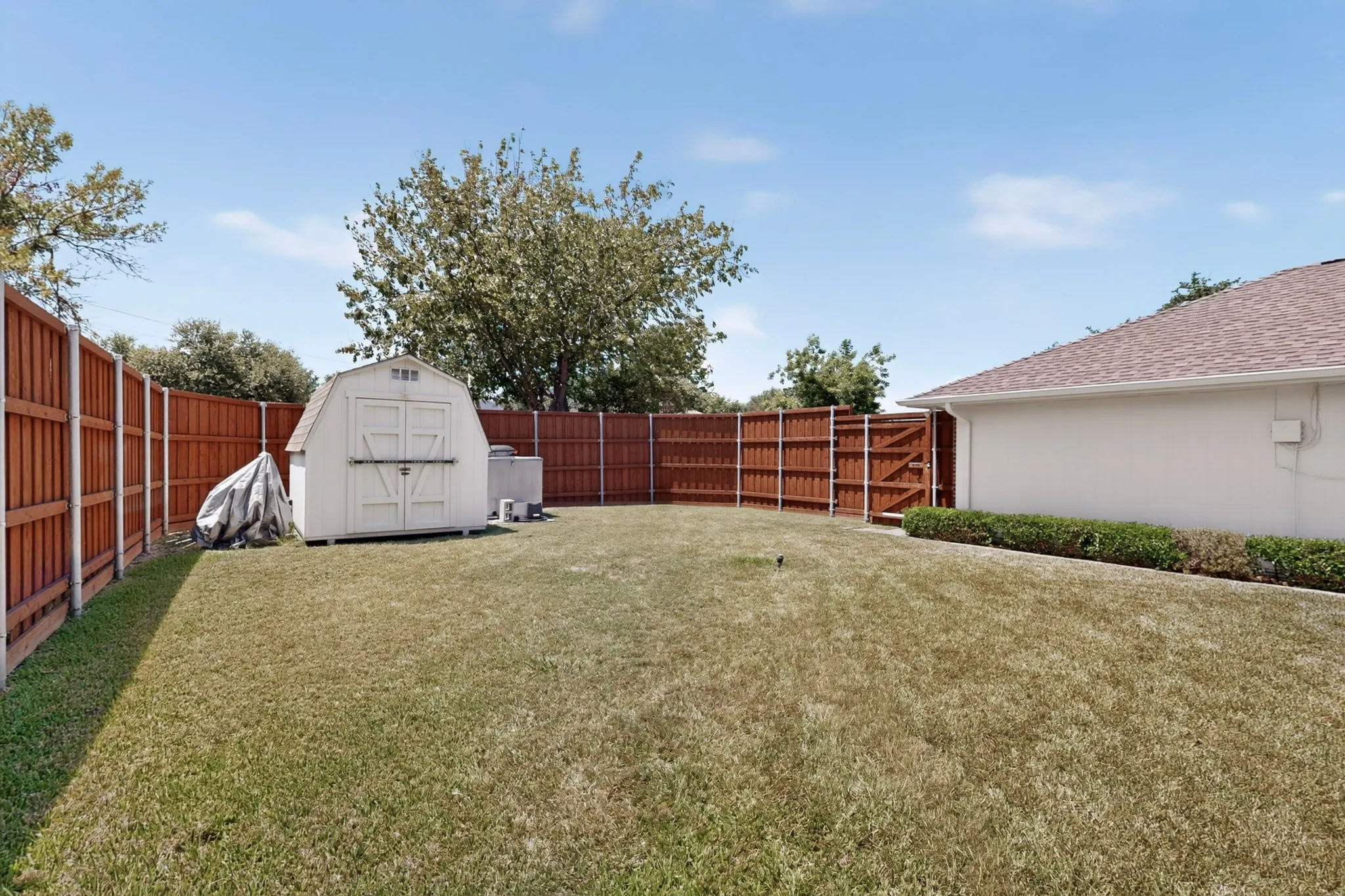 Expansive backyard featuring a privacy fence, a storage shed, and a gated entry