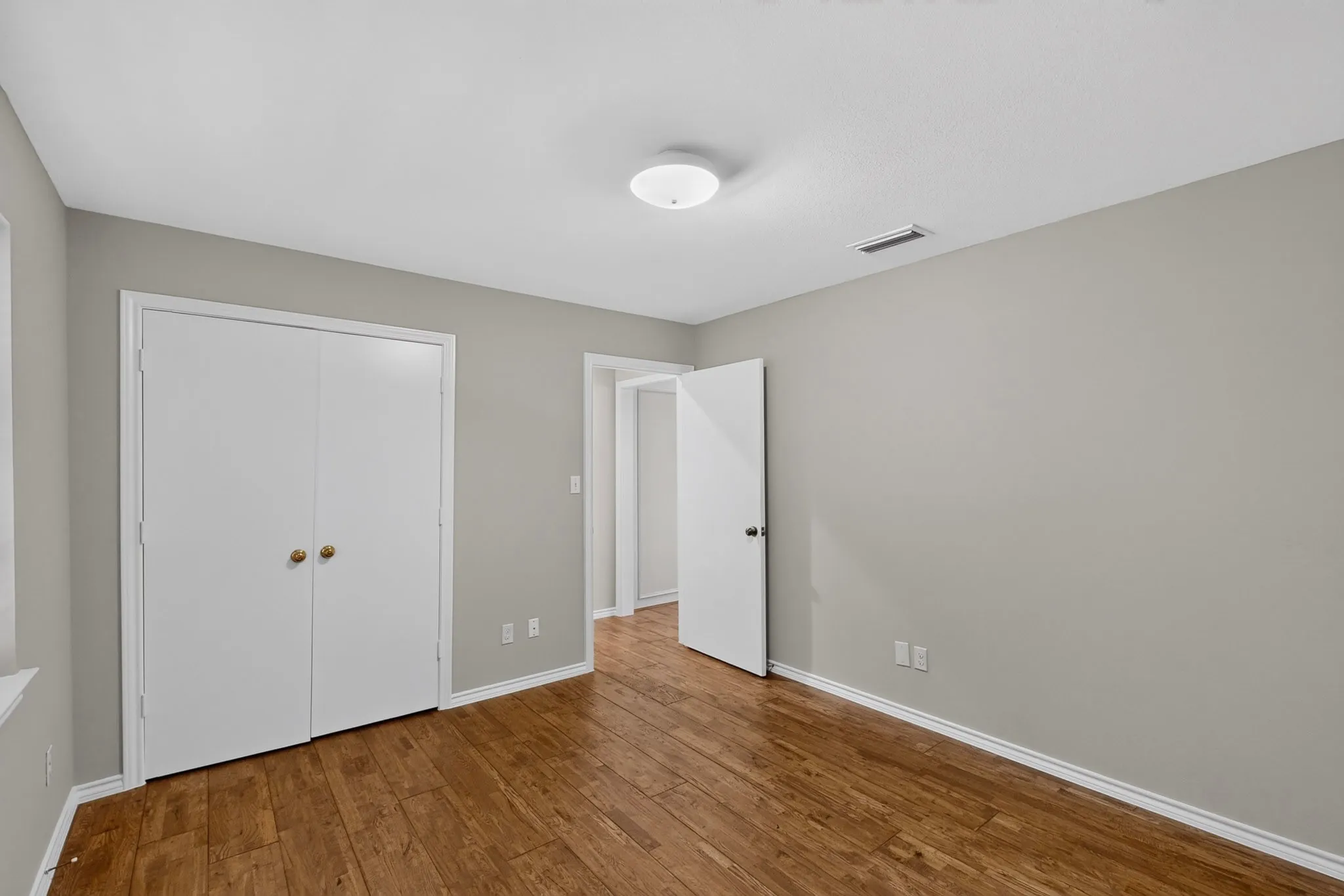 Wood-finish flooring, white walls, and a ceiling-mounted light fixture