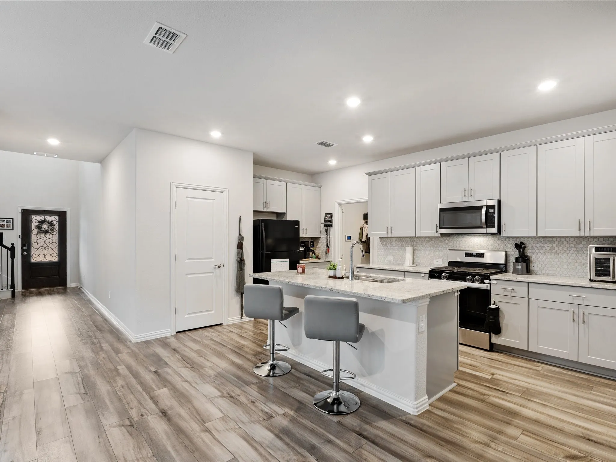 Modern kitchen featuring white cabinetry, quartz countertops, and stainless steel appliances including a built-in microwave and electric range