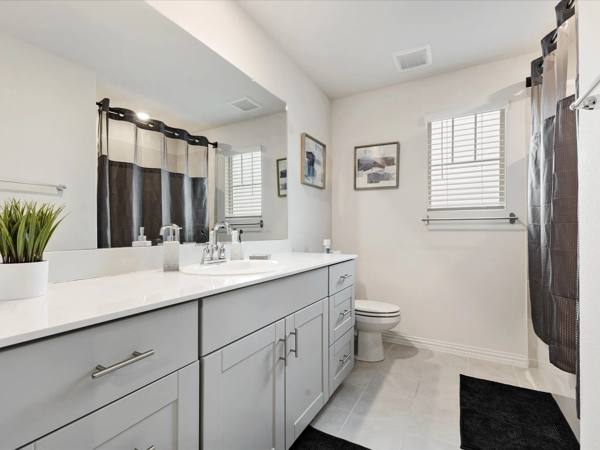White countertop vanity with undermount sink, light gray cabinetry, and chrome fixtures