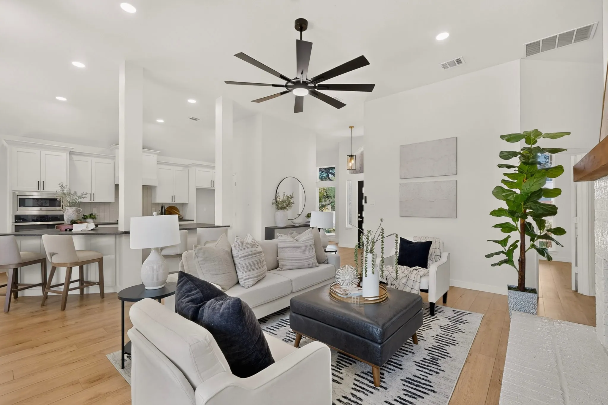 Spacious living area featuring high ceilings, wood-finish flooring, and a modern ceiling fan