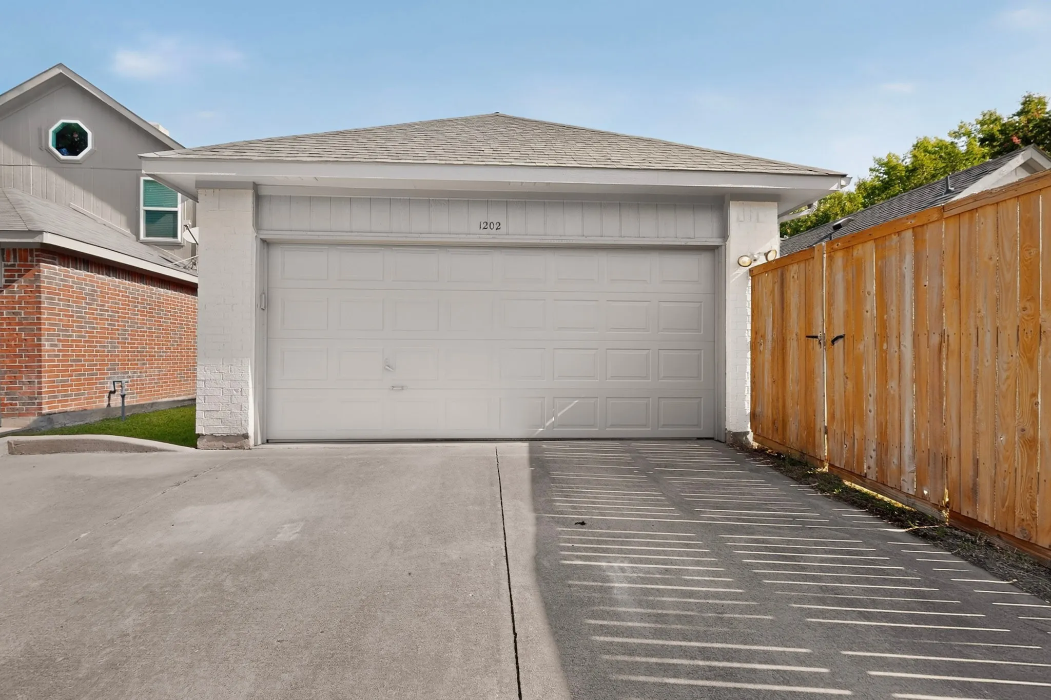 Attached garage with a panel-style door, concrete driveway, and wood privacy fence