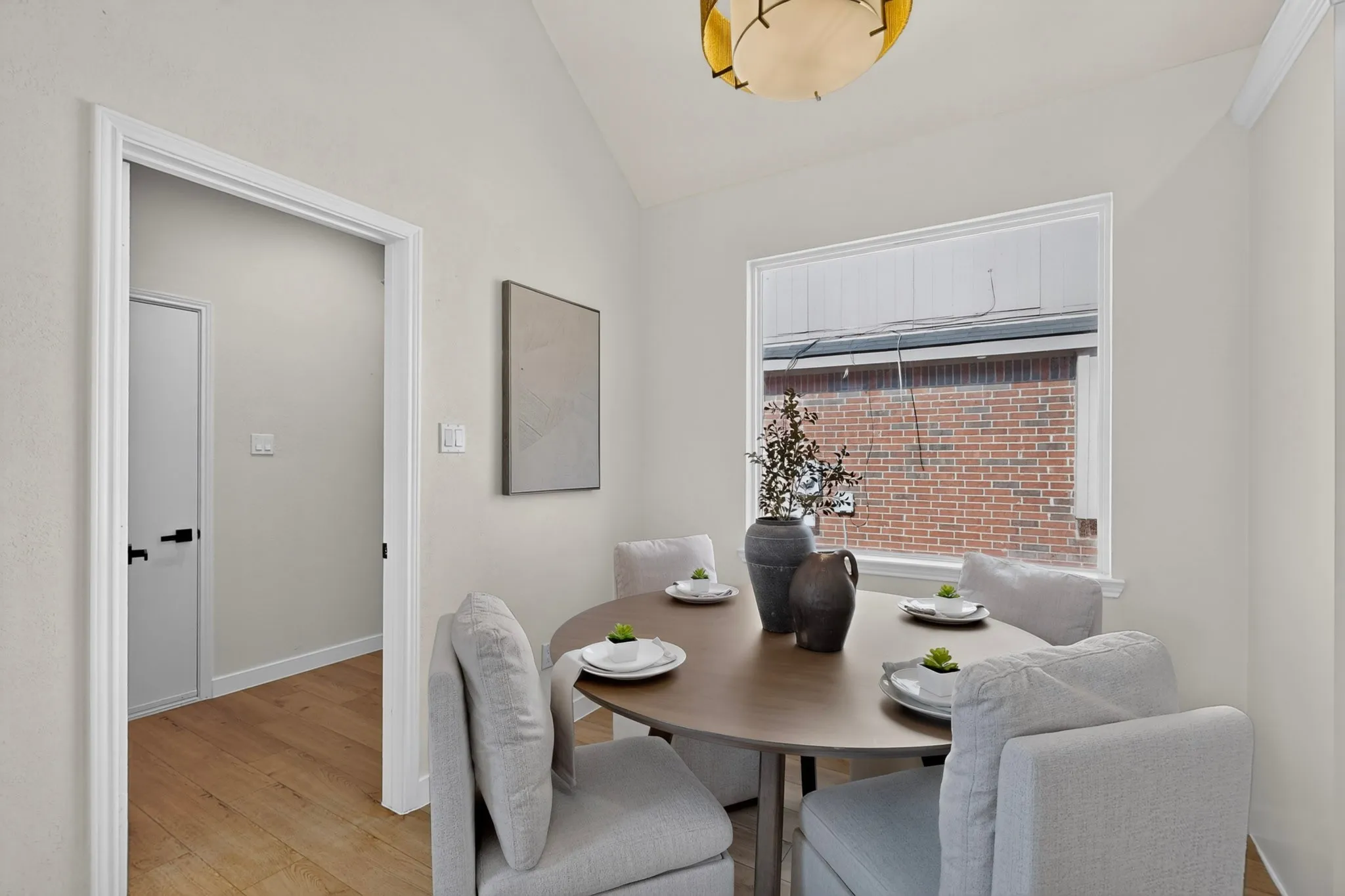 Vaulted ceiling with a contemporary light fixture, wood-finish flooring, and white trim throughout