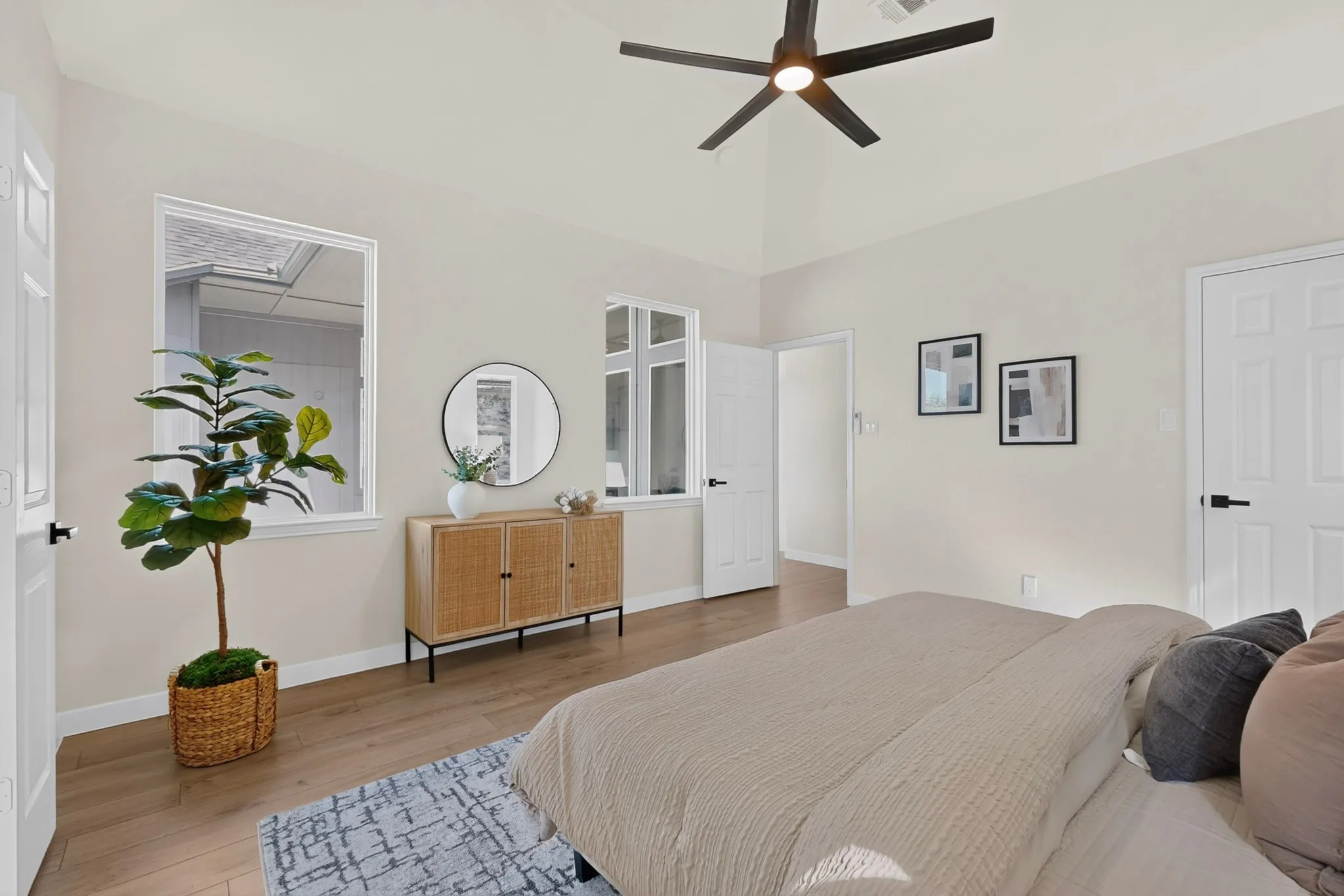 Vaulted ceiling with a black ceiling fan, recessed windows, wood-finish flooring, and white paneled doors with black hardware