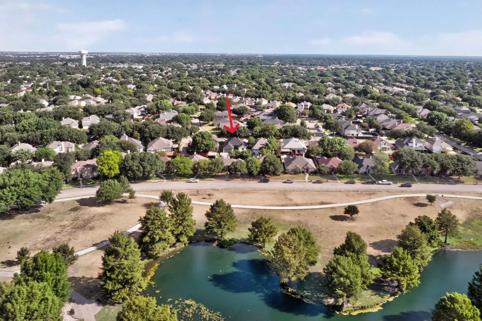 Residential neighborhood with mature trees, established housing, and a nearby pond with surrounding green space