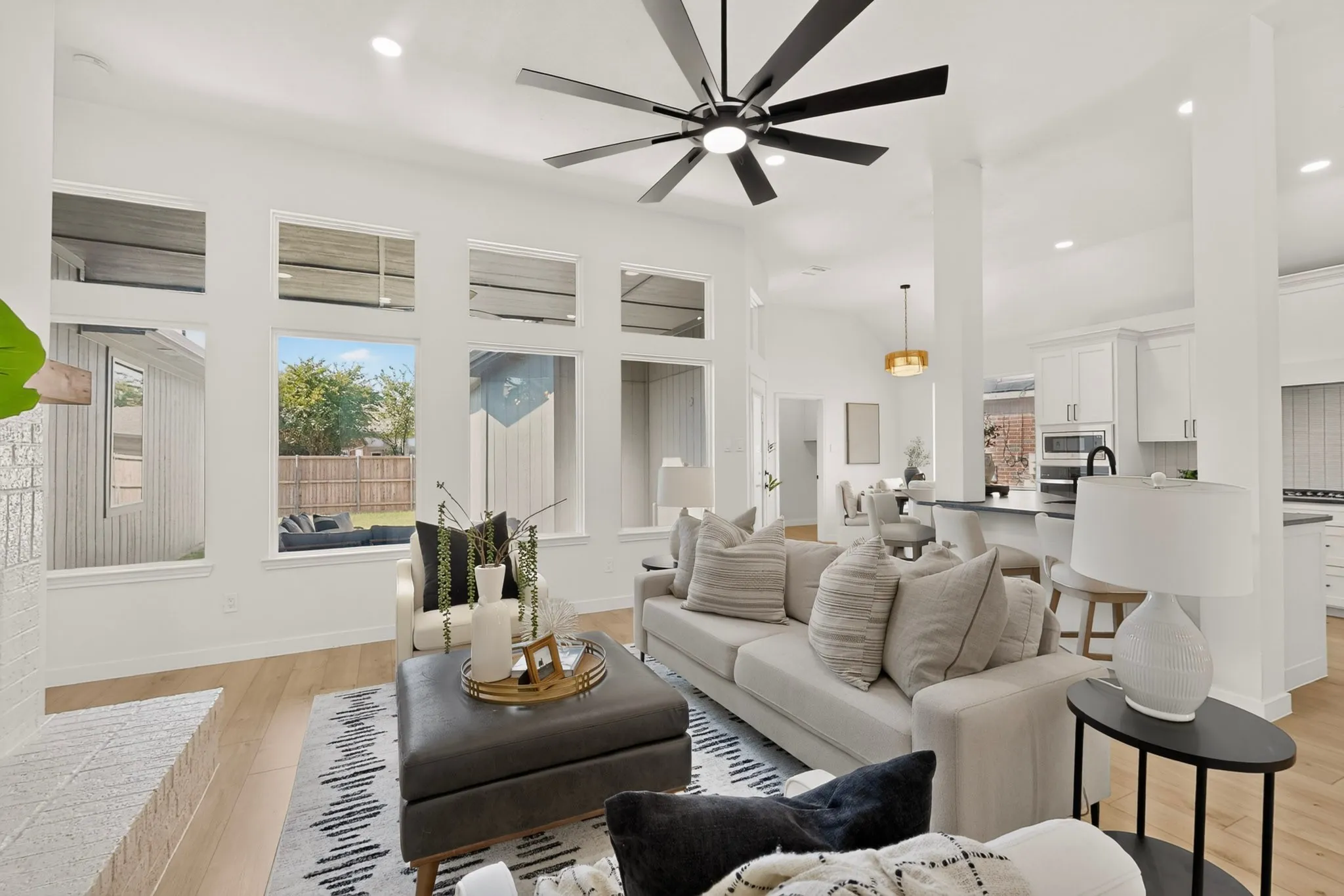 Living space with vaulted ceilings, recessed lighting, wood-finish flooring, a contemporary ceiling fan, and a built-in fireplace