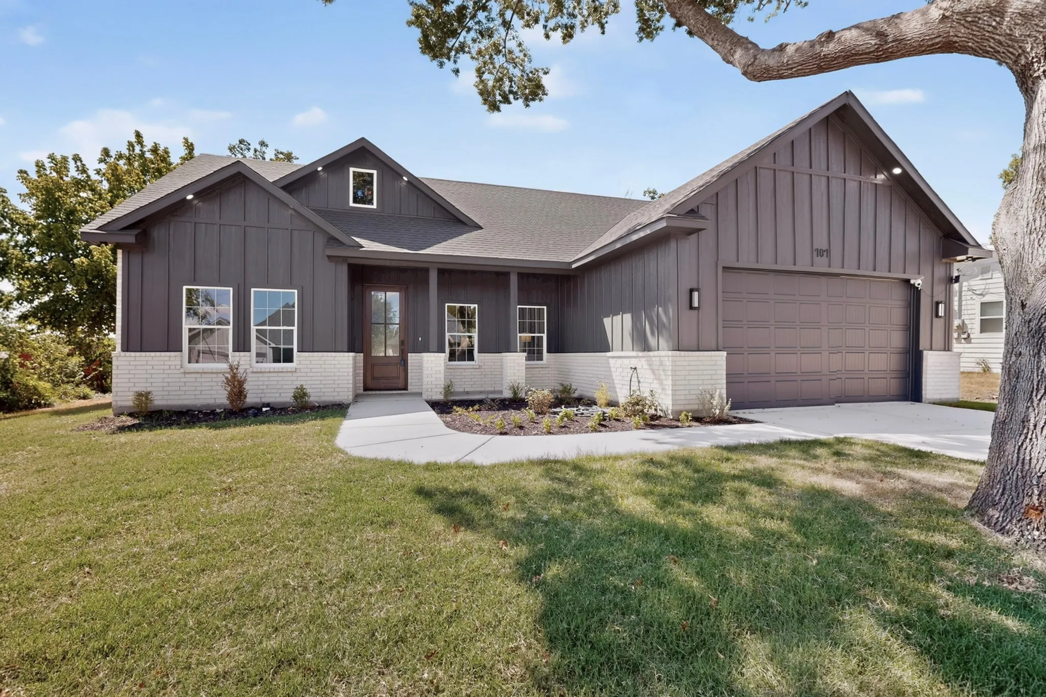 Contemporary exterior with vertical panel siding and a light brick wainscot