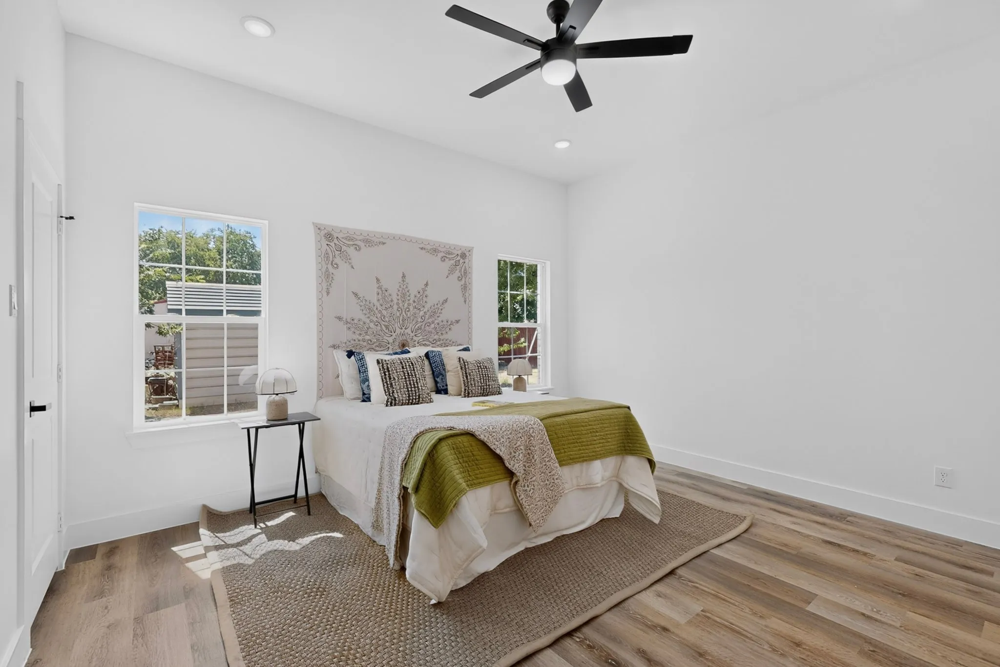 Vaulted ceiling with a ceiling fan, recessed lighting, wood-finish flooring, and white walls with trim