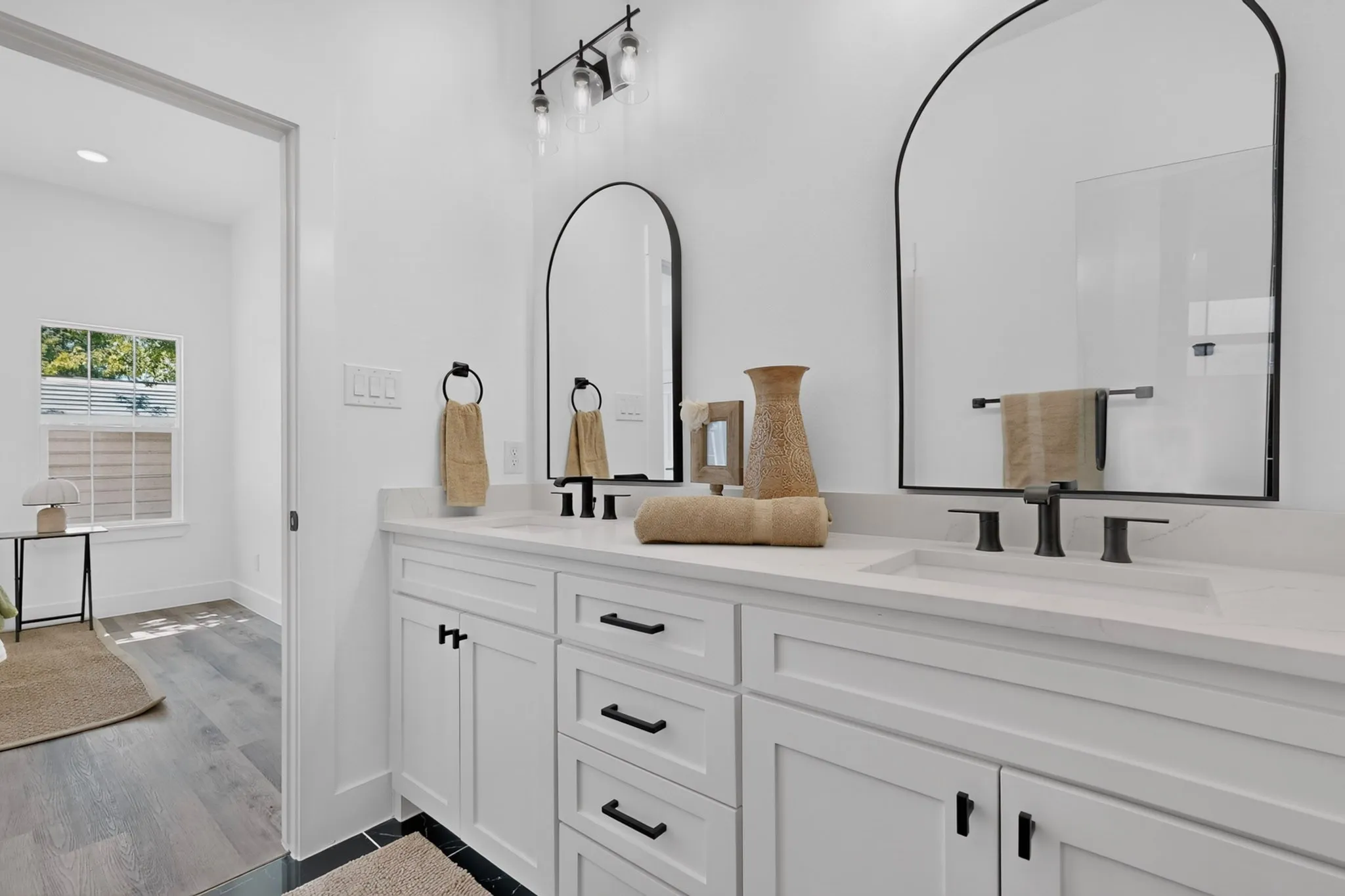 Dual vanity with white cabinetry and black hardware, set against white​​‌​​​​‌​​‌‌​‌‌​​​‌‌​‌​‌​‌​​​‌​​ walls
