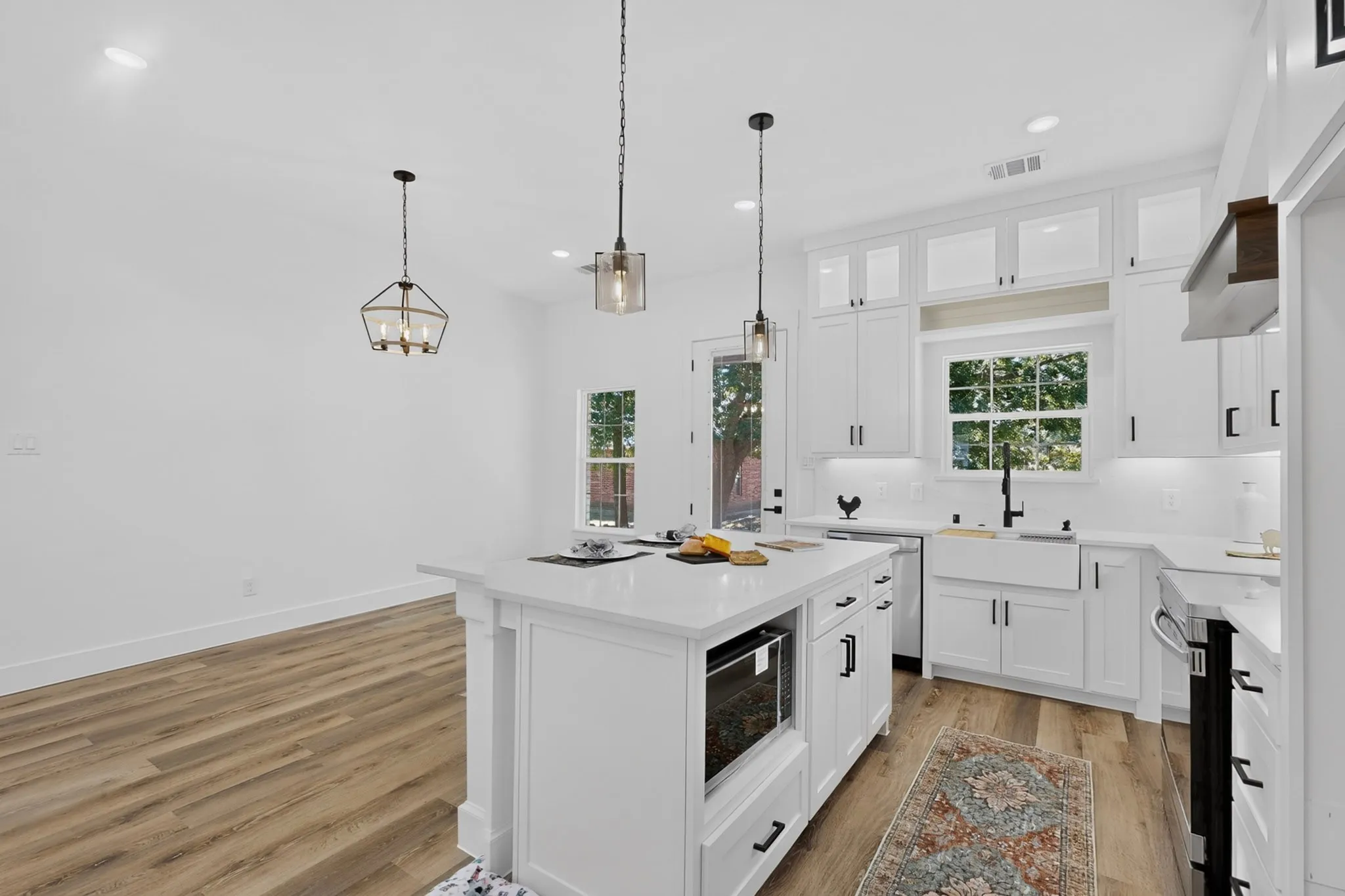 Kitchen featuring a central island, white cabinetry, farmhouse sink, quartz countertops, and wood-finish flooring