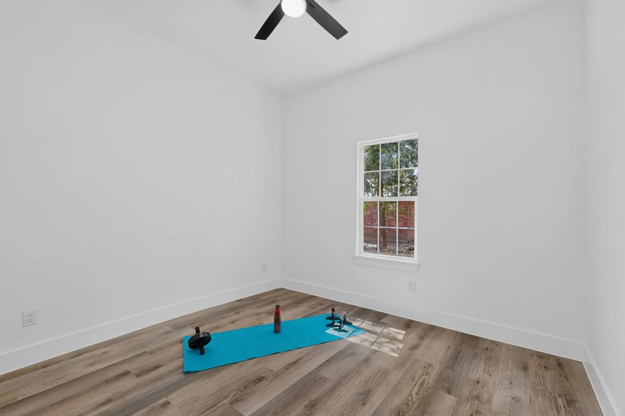 Wood-finish flooring, white walls, and a ceiling fan