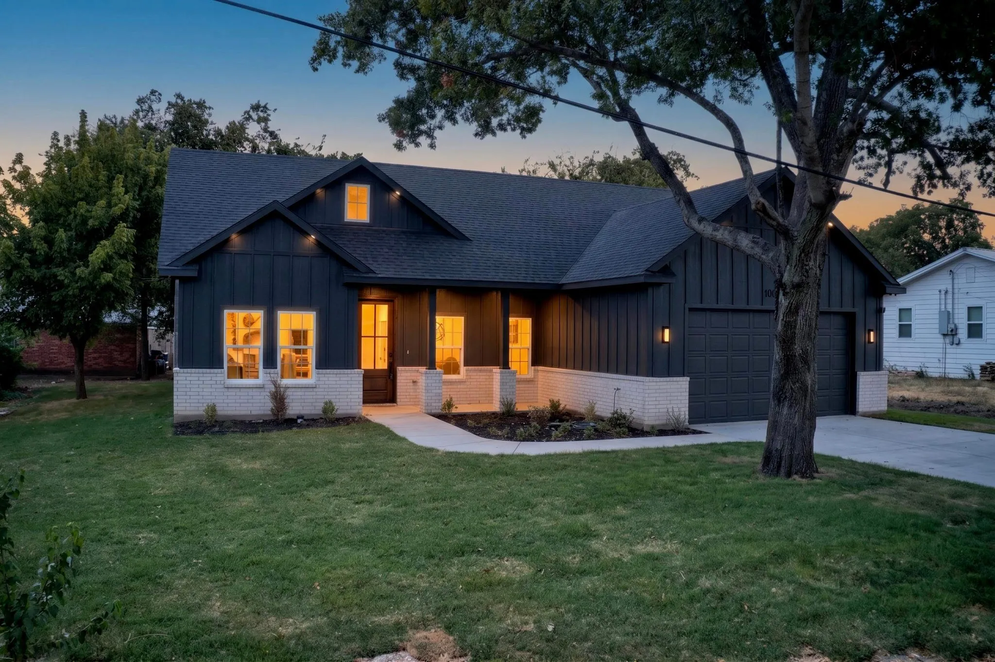 Board and batten siding, light-colored brick detailing, and a dark asphalt shingle roof
