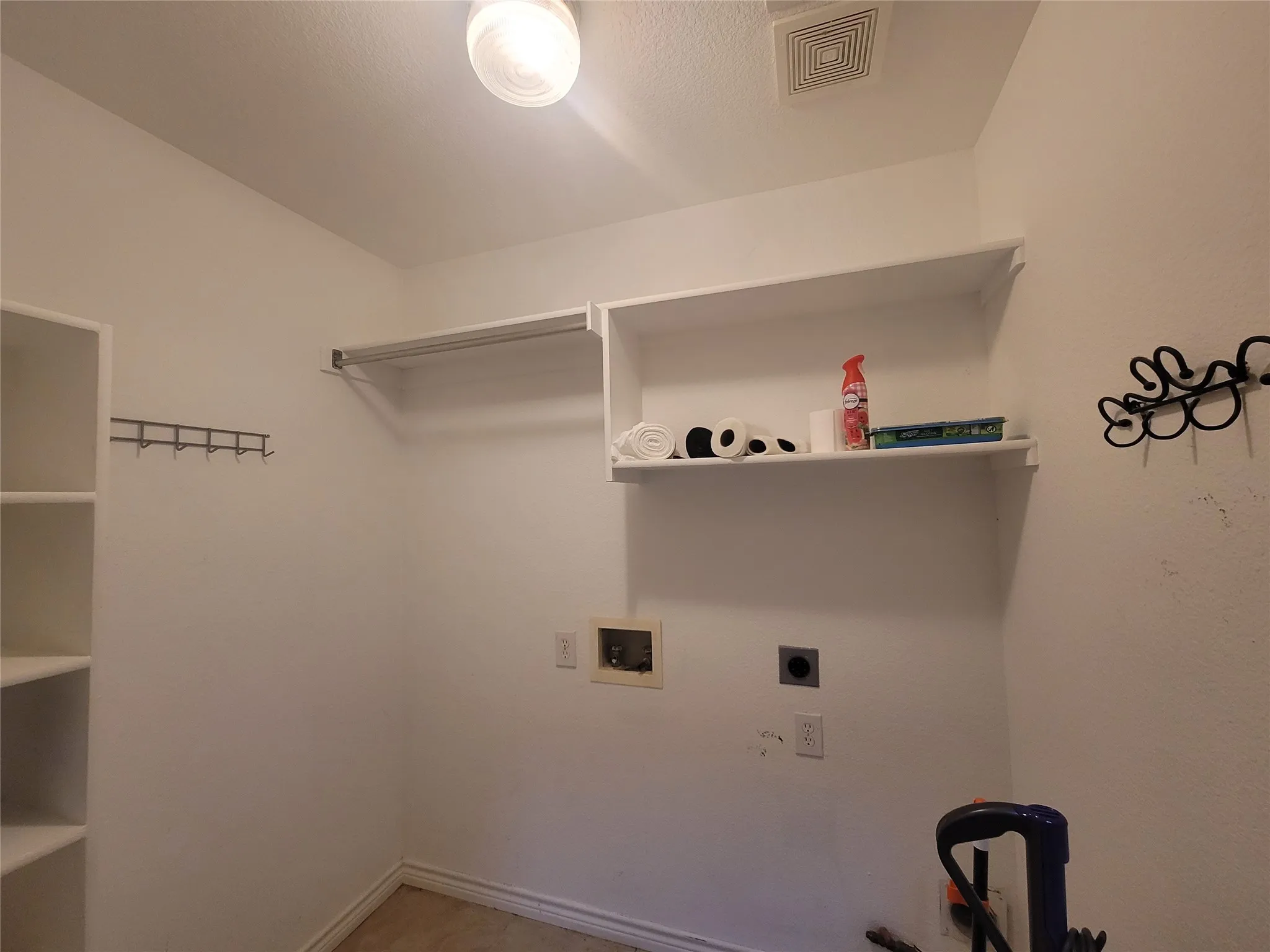Built-in shelving, white walls, overhead light fixture, and ceiling vent