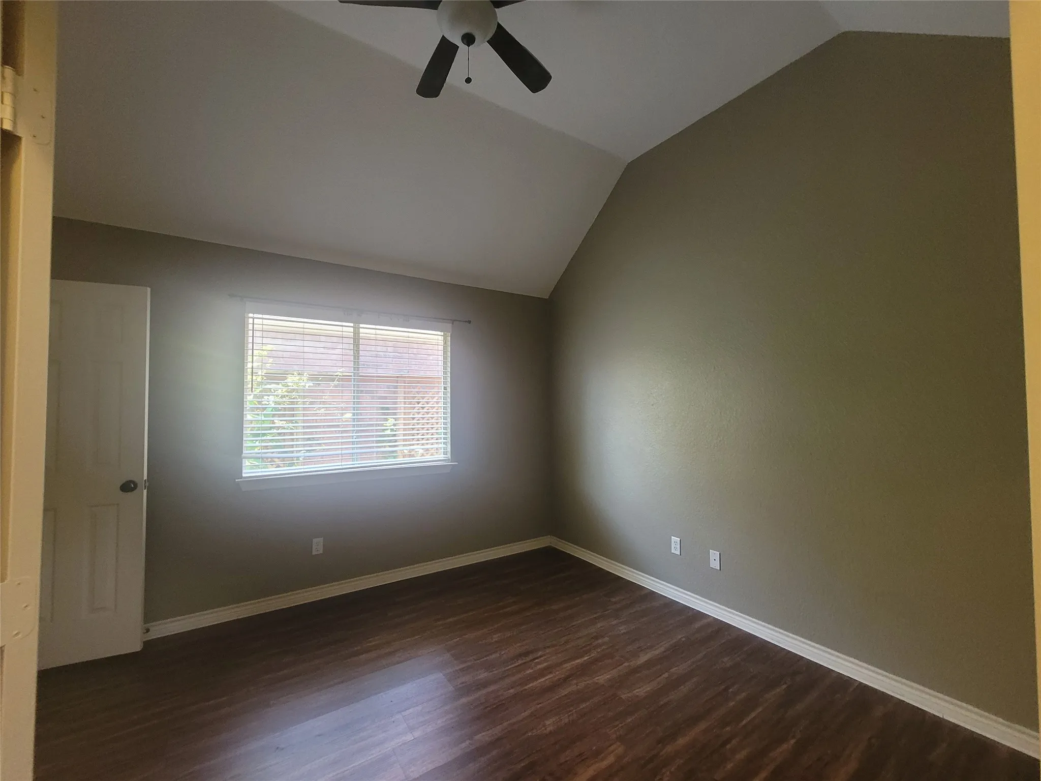 Vaulted ceiling with a ceiling fan, wood-finish flooring, and a window with horizontal blinds