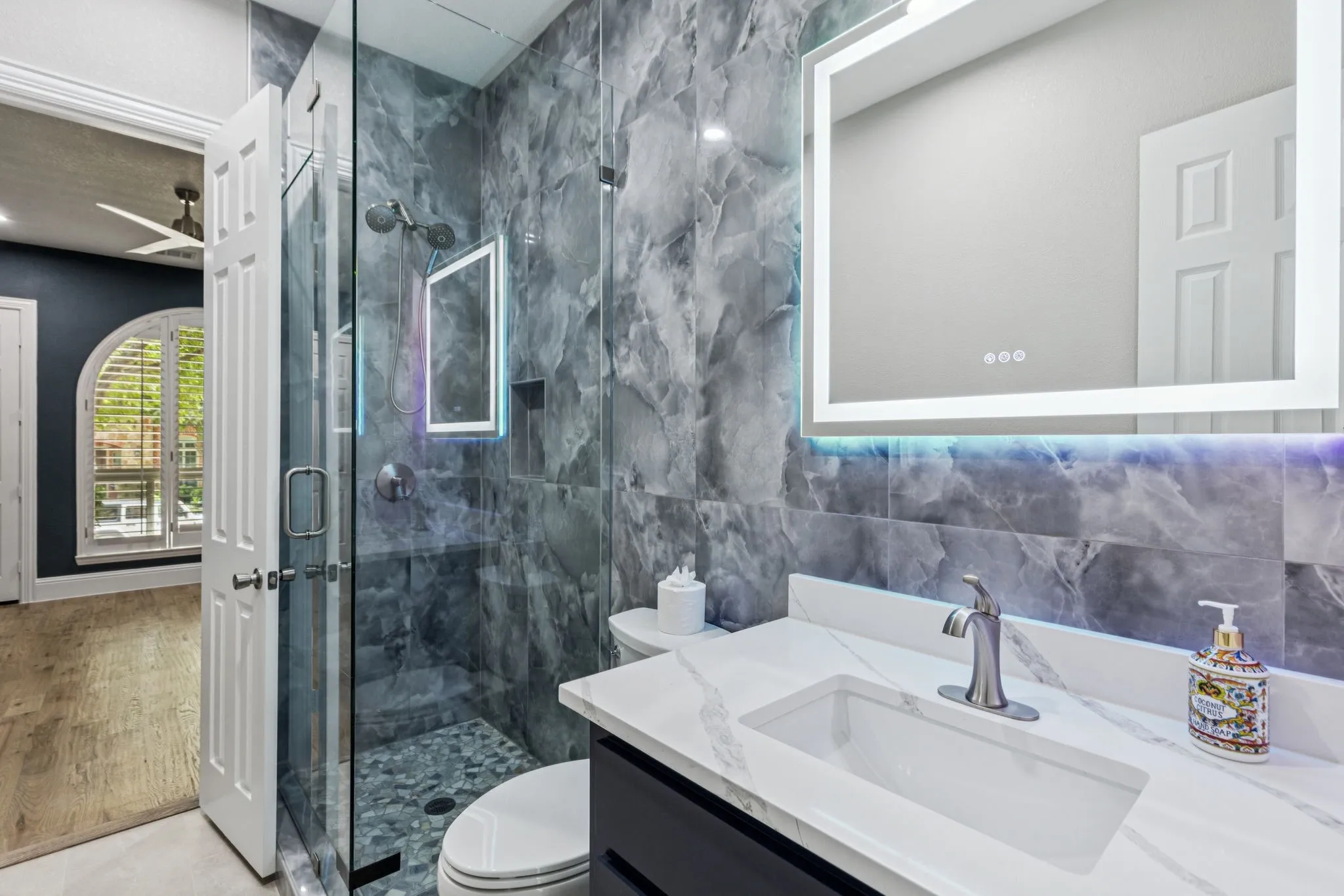 Glass-enclosed shower with pebble flooring, integrated wall niche, and dual shower heads