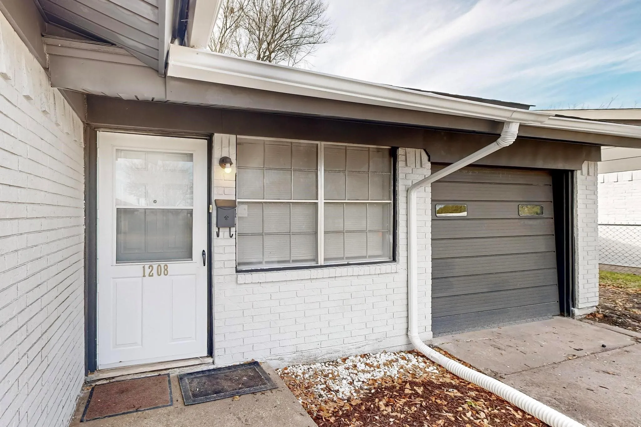 White brick exterior with a front entry door and an attached garage