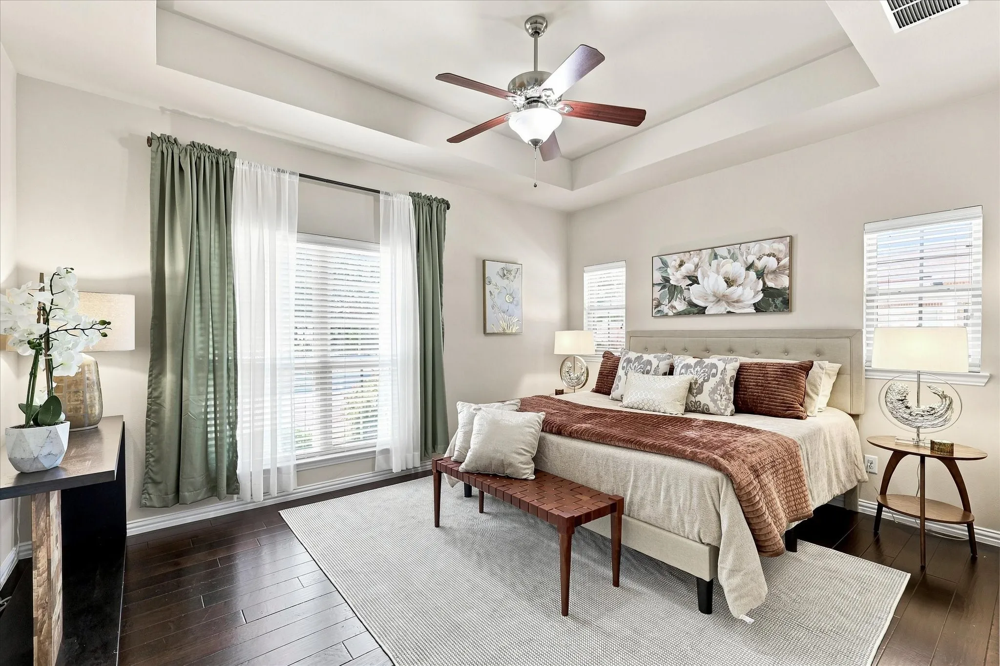 The spacious primary bedroom features beautiful wood floors and windows that fill the room with natural light, creating a comfortable and inviting retreat.