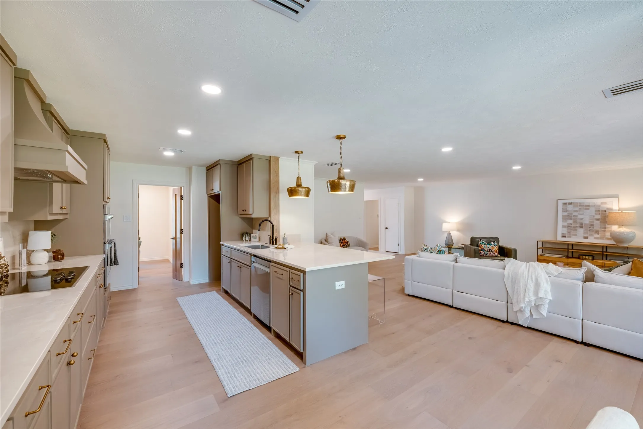 Open-concept kitchen and living area featuring wood-finish flooring, recessed lighting, a kitchen island with pendant lighting, and contemporary cabinetry